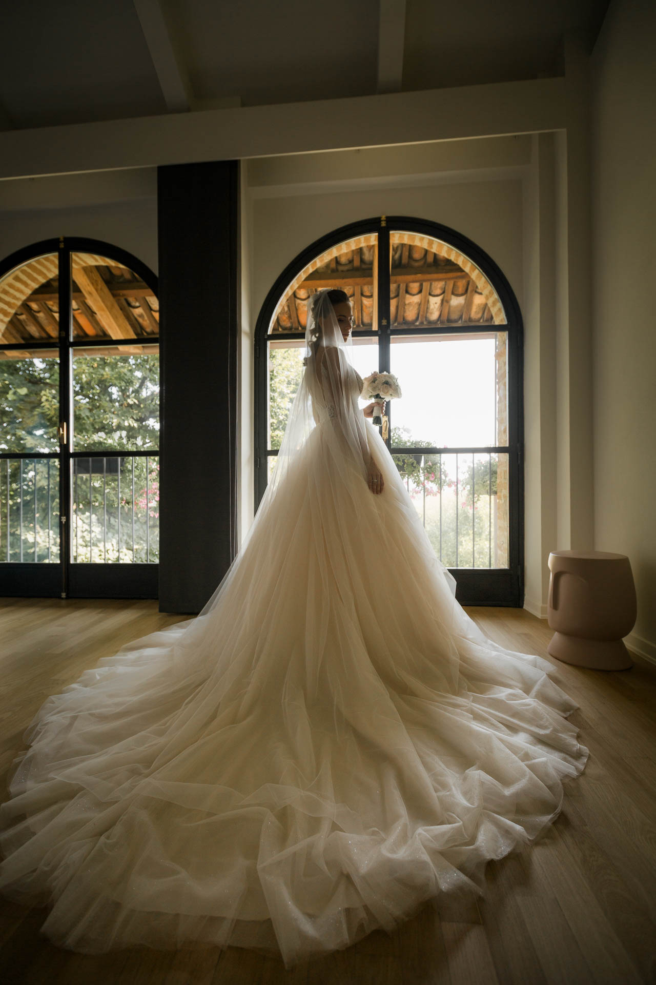La sposa davanti alla finestra ad arco, con lo strascico sul pavimento