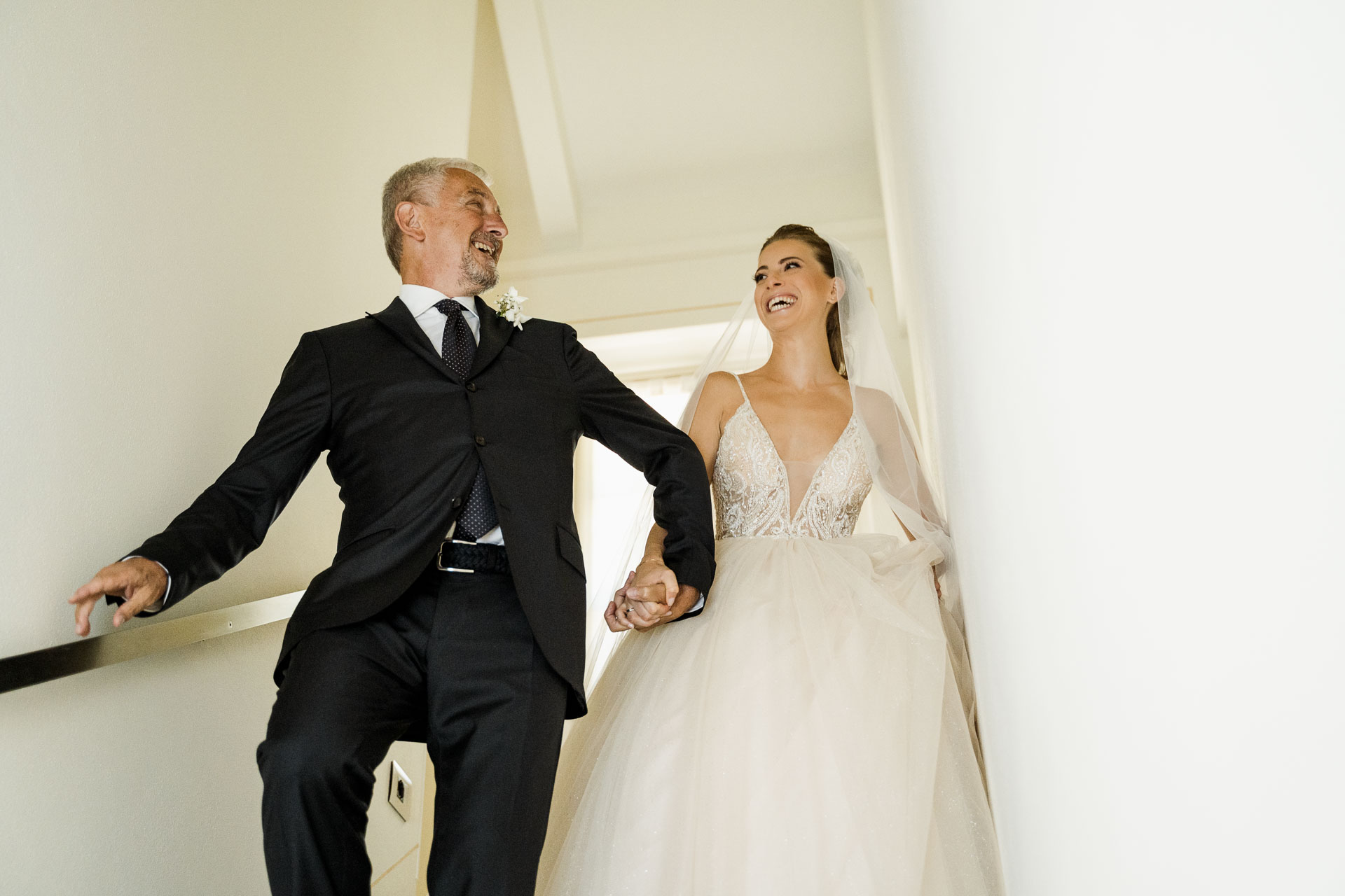 Il papà accompagna la sposa giù per le scale, ridendo