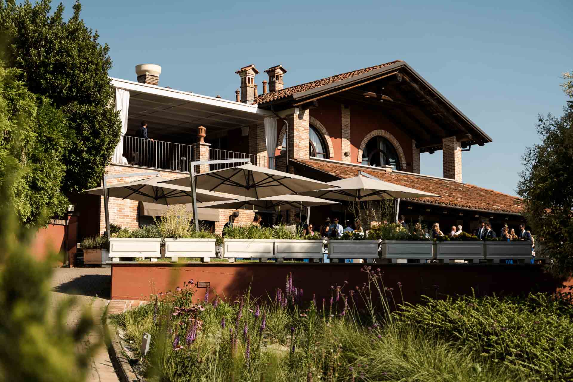 La Madernassa, con la terrazza, gli ombrelloni e il giardino fiorito