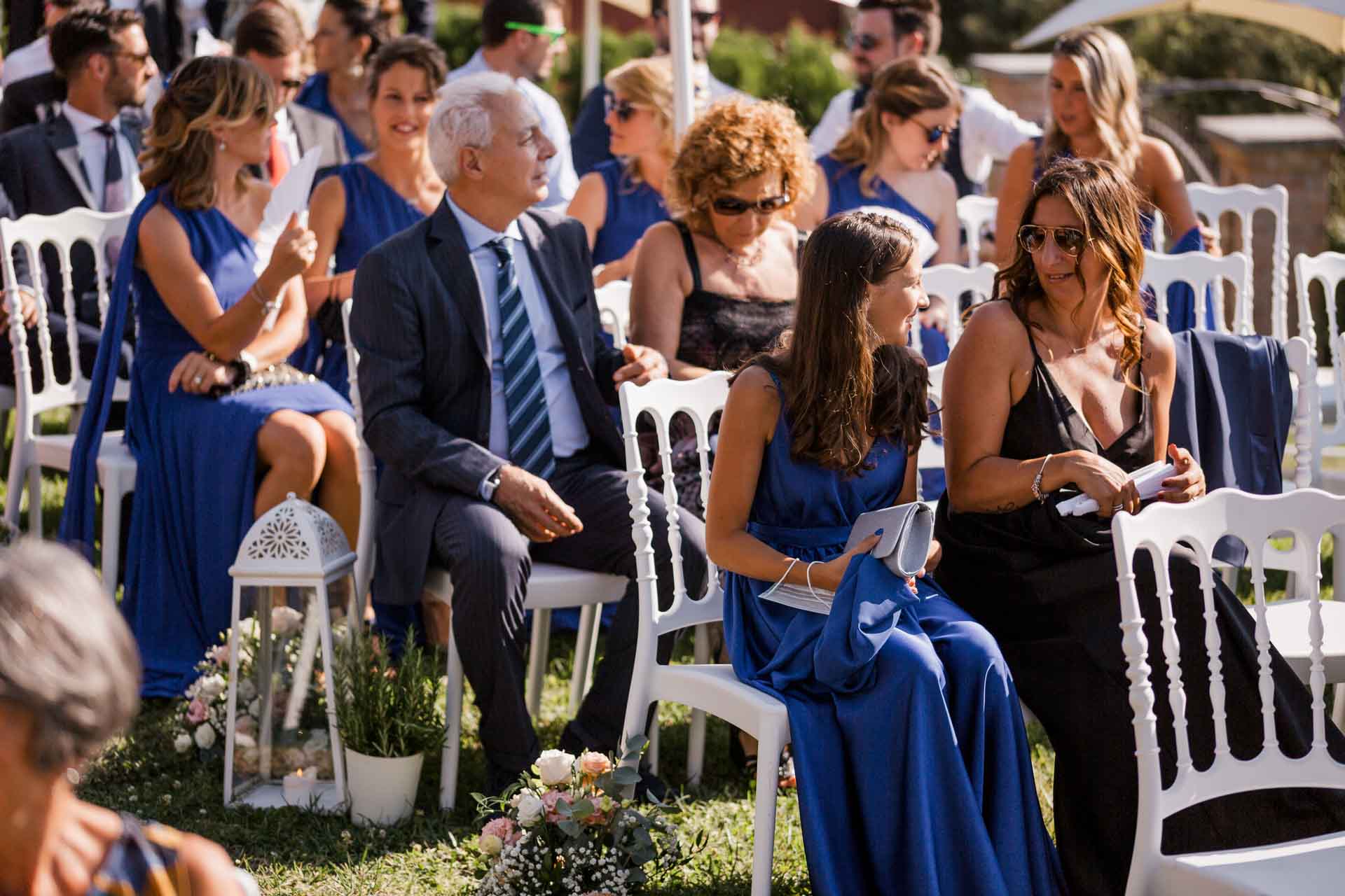 Gli invitati seduti tra le sedie bianche e le lanterne