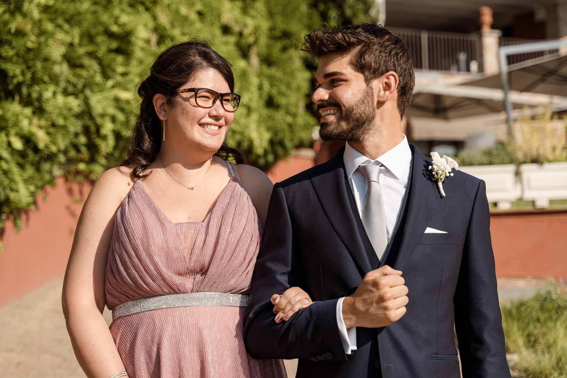 Lo sposo sorride sottobraccio alla ragazza in rosa