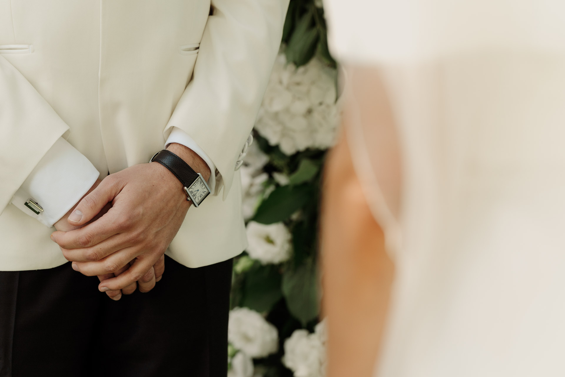 Le mani dello sposo con l'orologio, accanto al velo