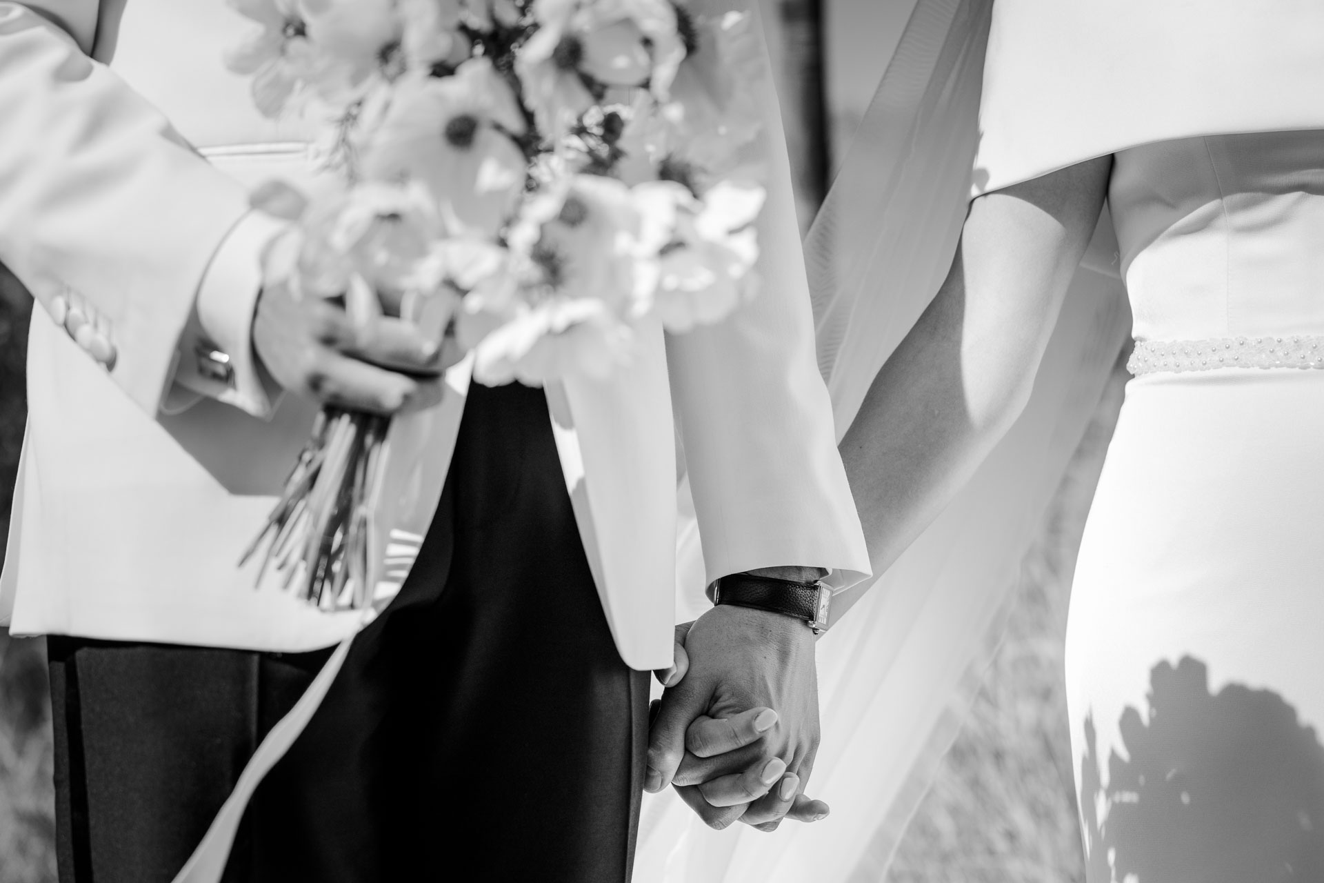 In bianco e nero, le mani degli sposi e il bouquet