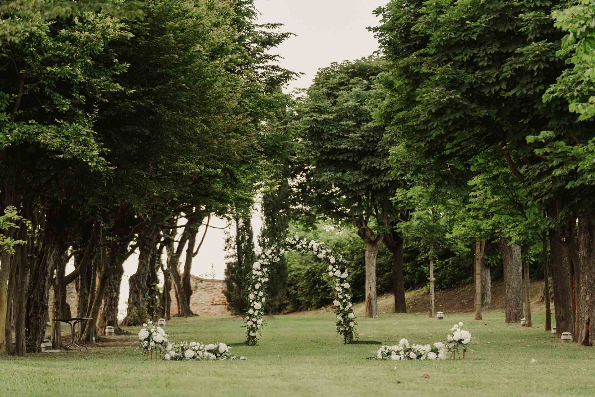 Il viale d'alberi e l'arco di fiori nel parco del Relais Sant'Uffizio