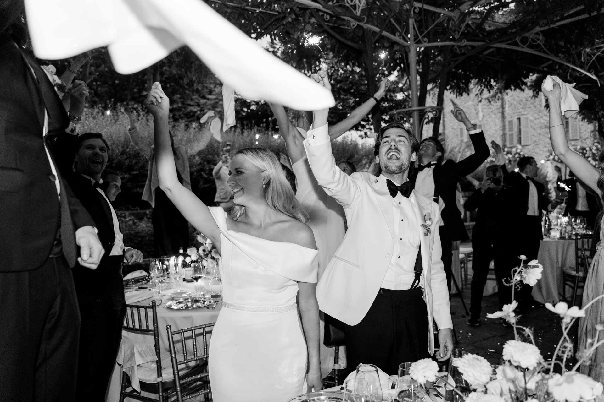 In bianco e nero, gli sposi e gli invitati sventolano i tovaglioli