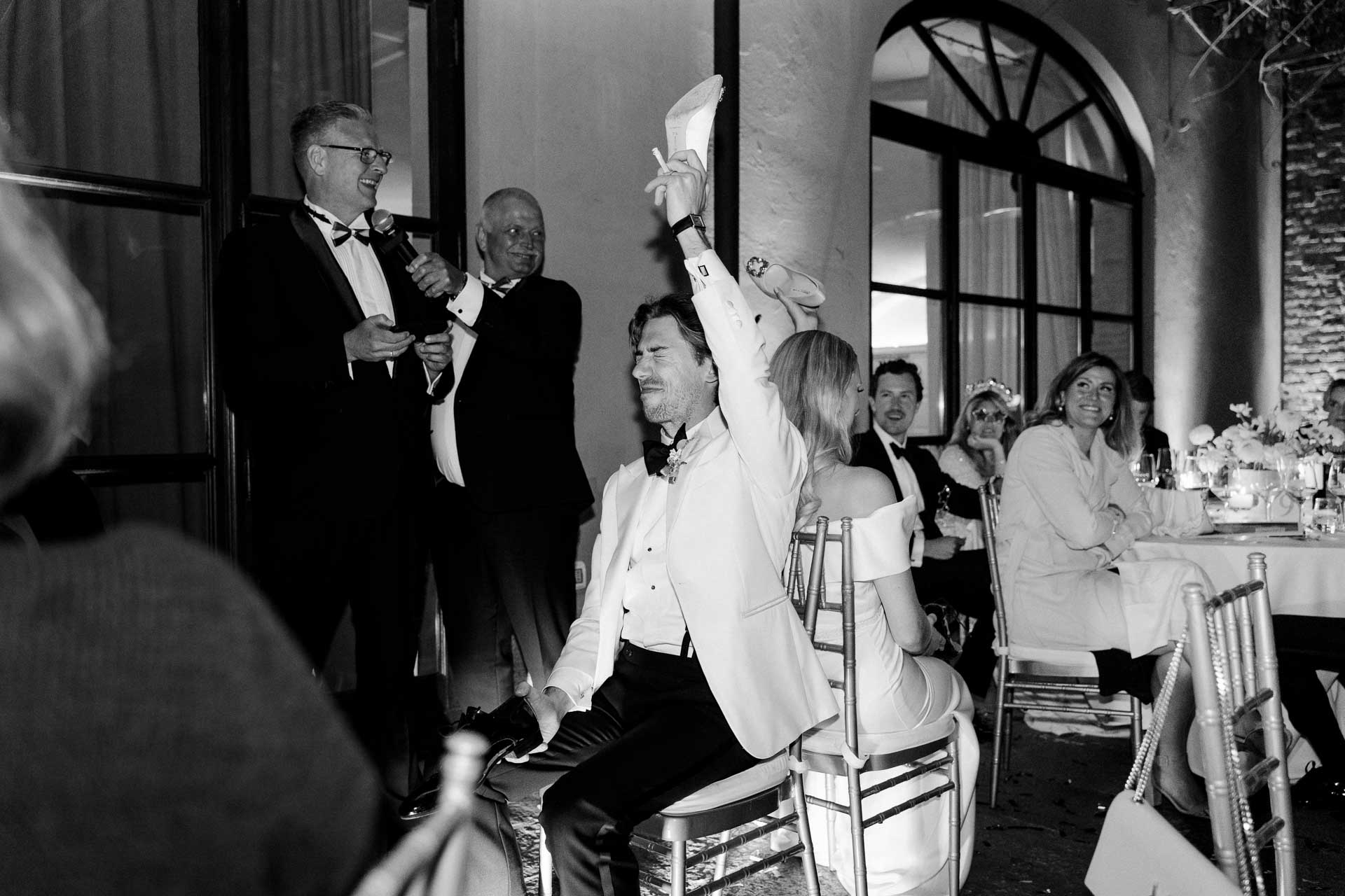 In bianco e nero, lo sposo festeggia in piedi sulla sedia