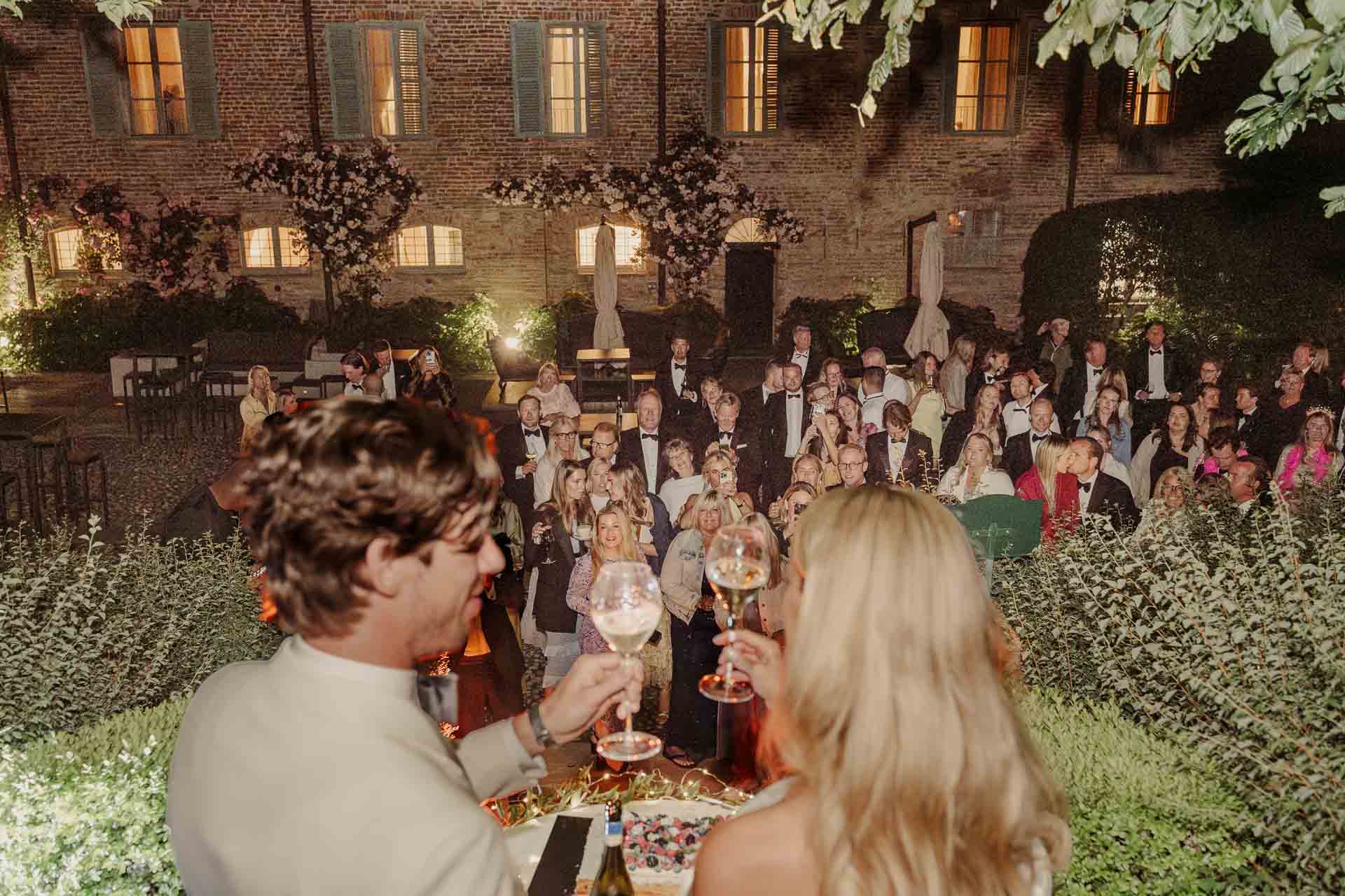 Gli sposi brindano davanti agli invitati nel giardino di notte
