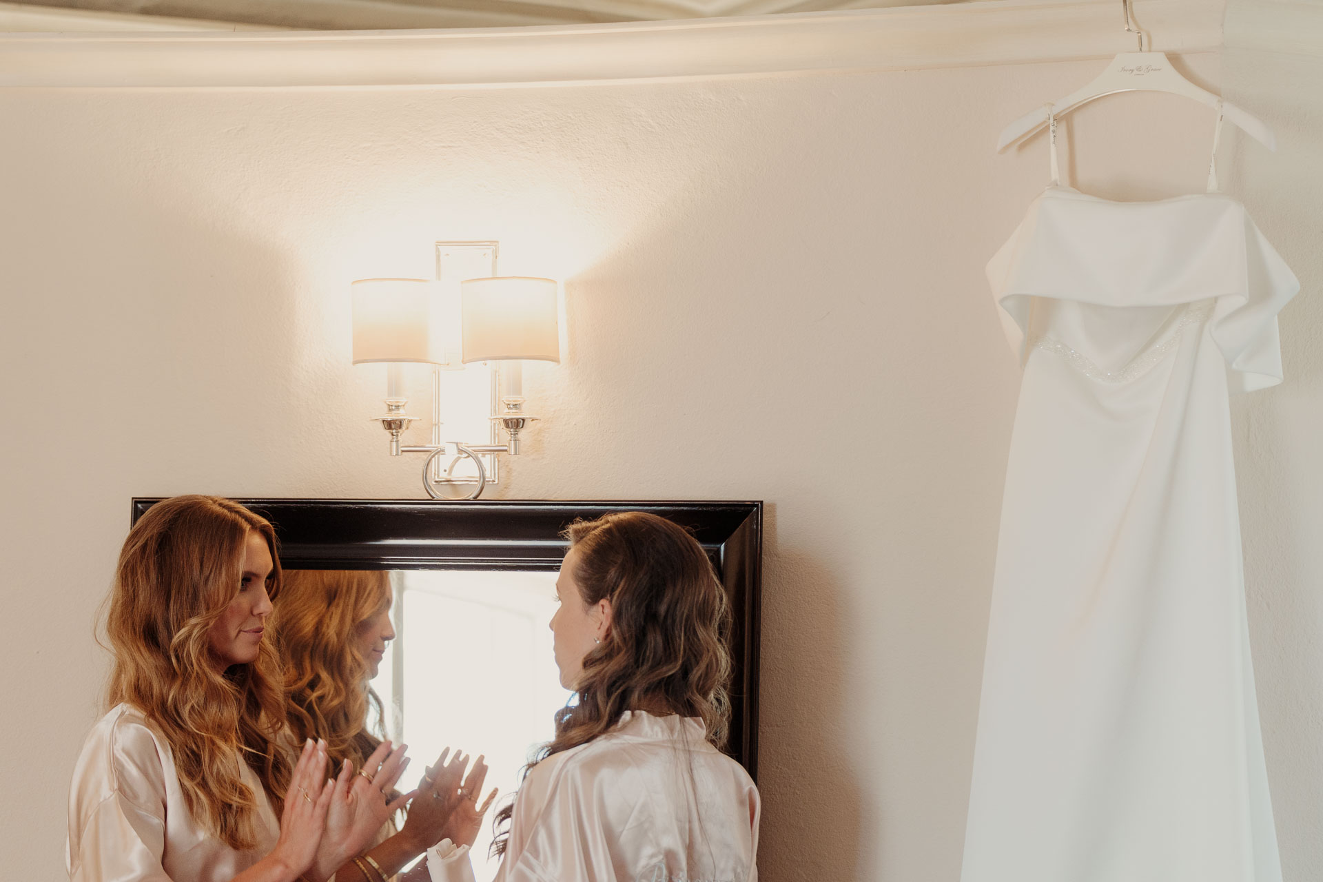 La sposa e le amiche davanti allo specchio, con l'abito appeso
