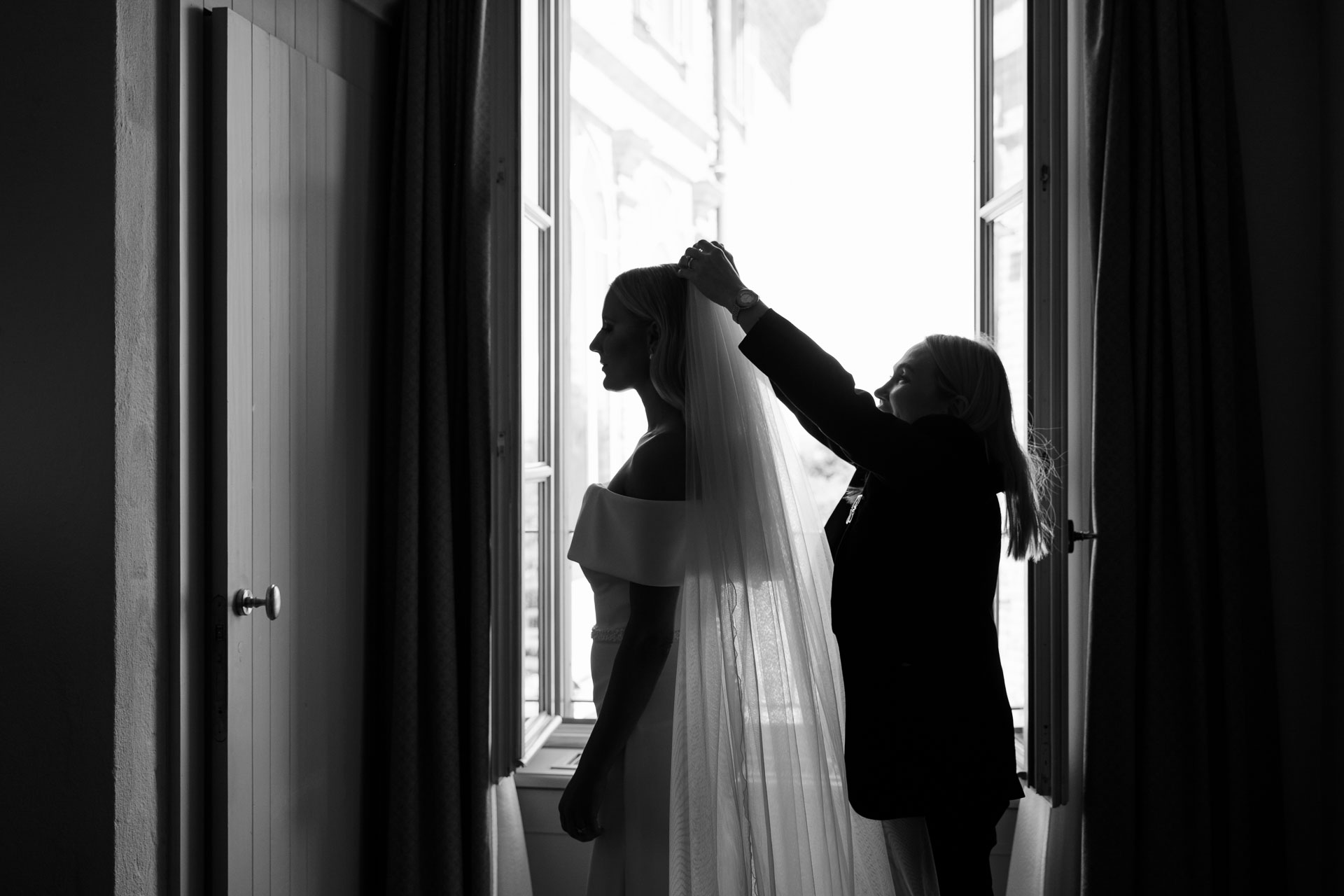 In bianco e nero, il velo sistemato alla sposa in controluce