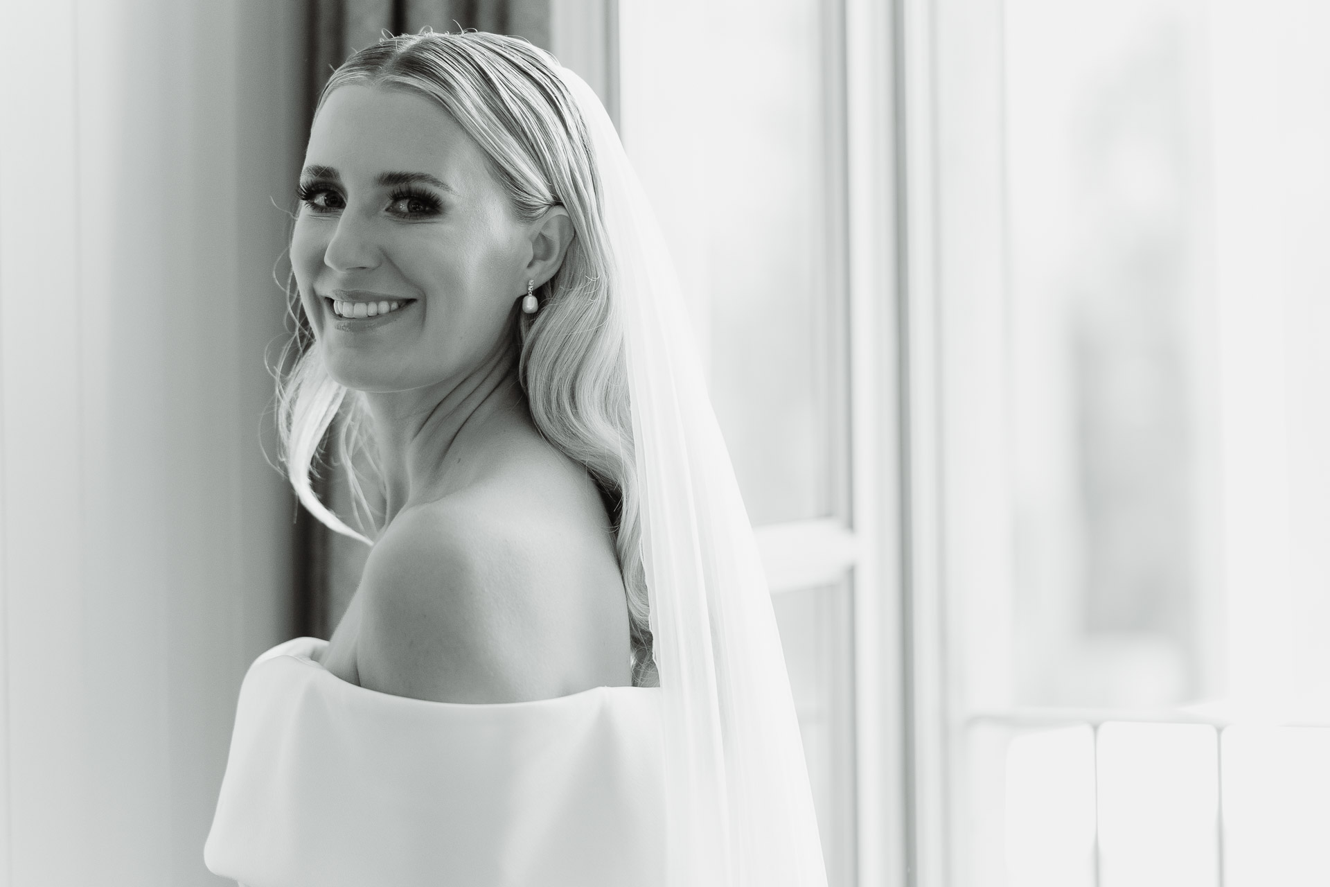 In bianco e nero, la sposa con il velo si volta sorridendo