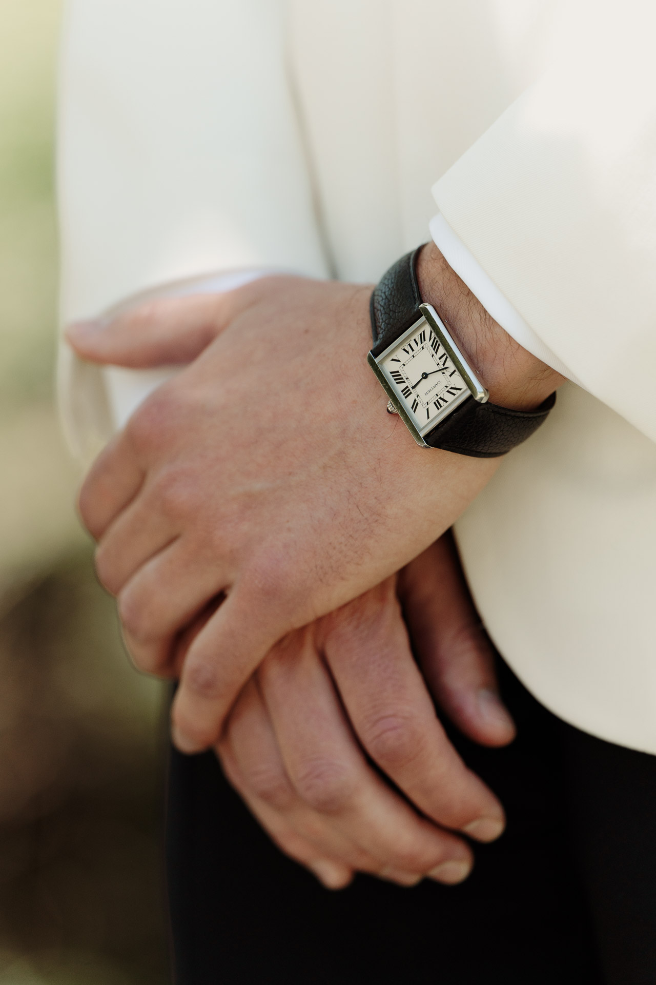L'orologio e le mani dello sposo sulla giacca bianca