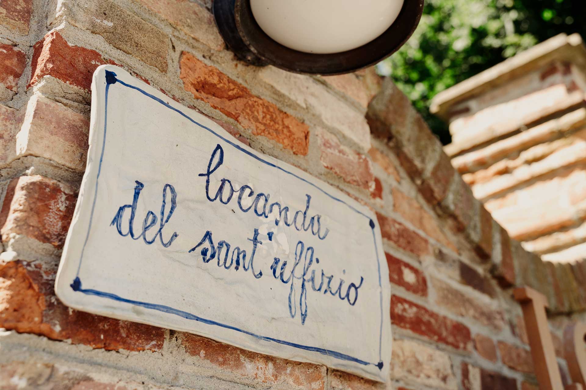L'insegna dipinta della Locanda del Sant'Uffizio sul muro di mattoni