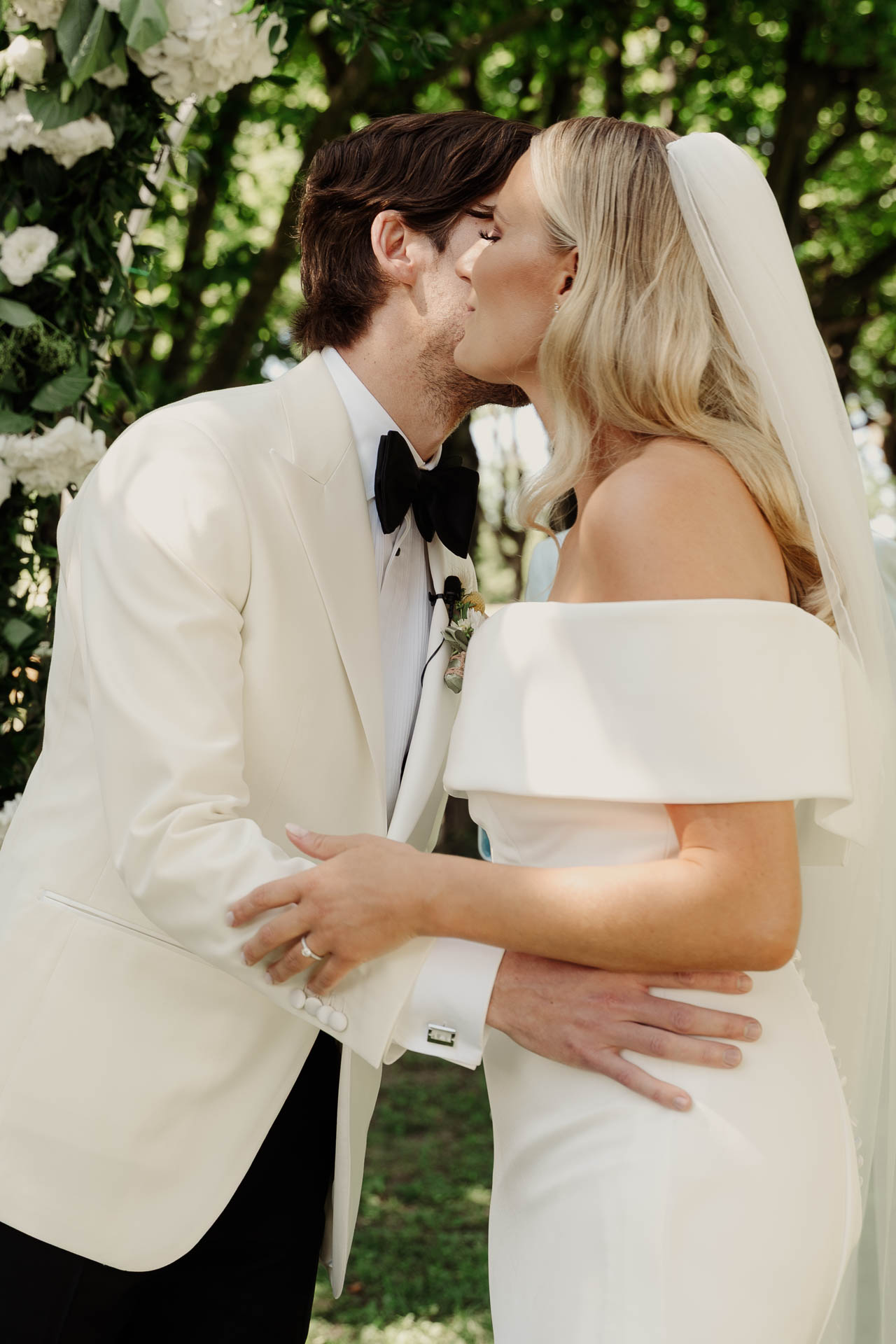 Il bacio degli sposi sotto l'arco di fiori