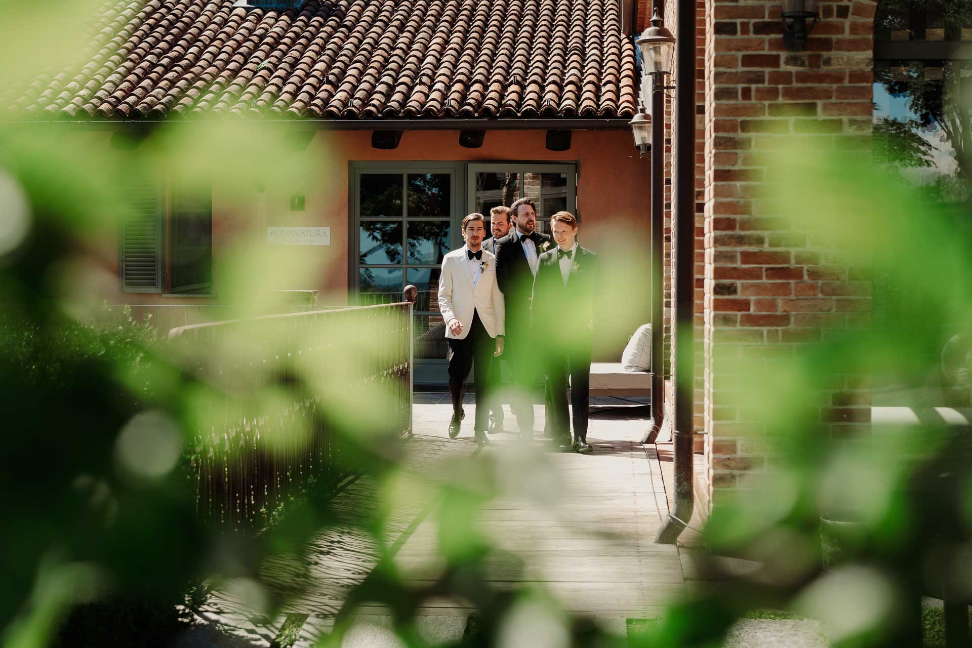 Lo sposo e gli amici escono dal relais, visti tra le foglie