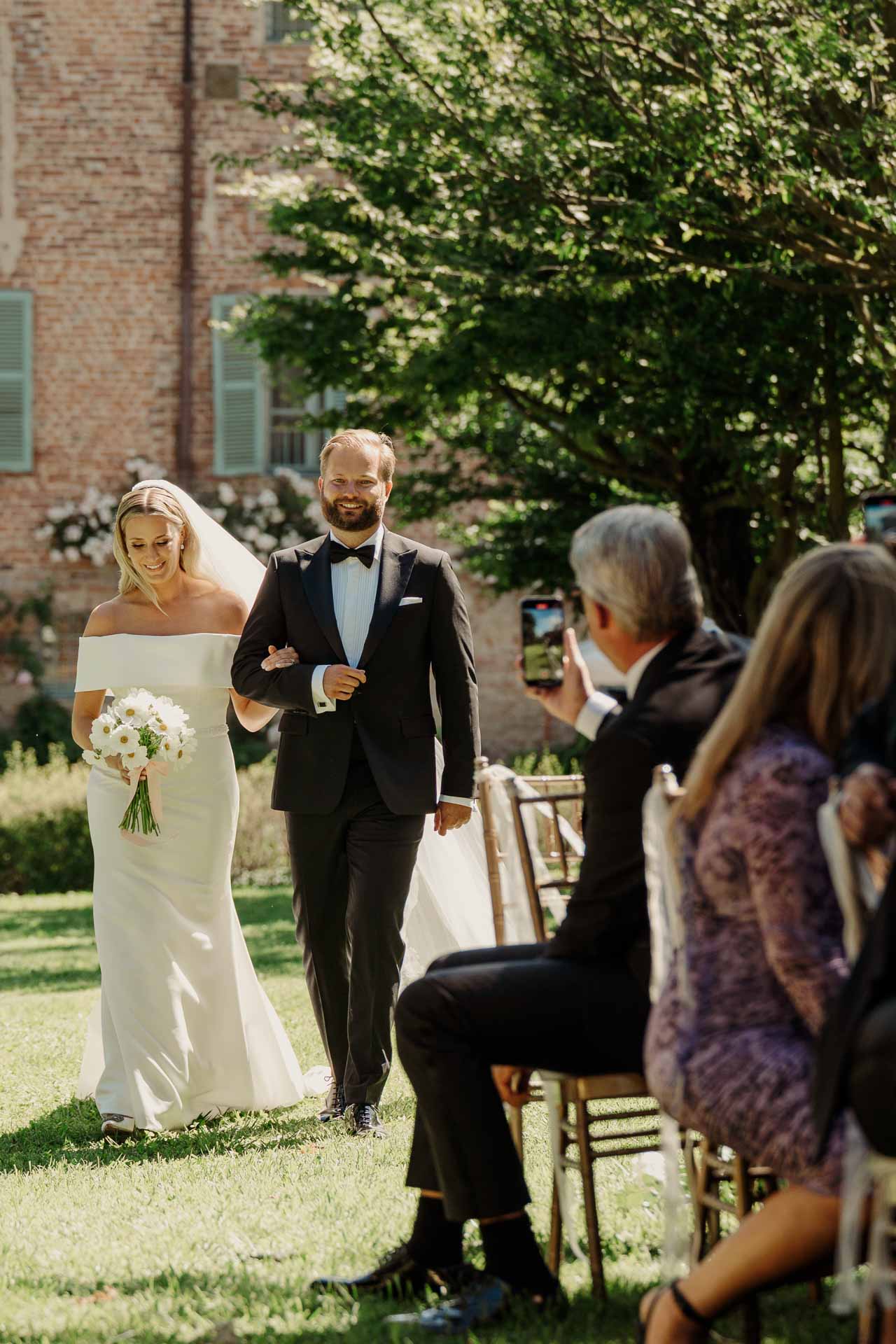 La sposa avanza sottobraccio verso la cerimonia