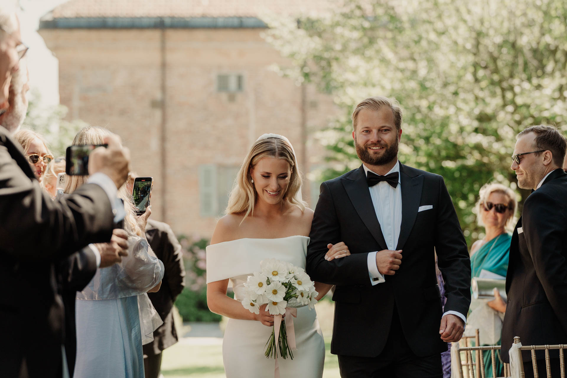 La sposa sorride sottobraccio, tra gli invitati