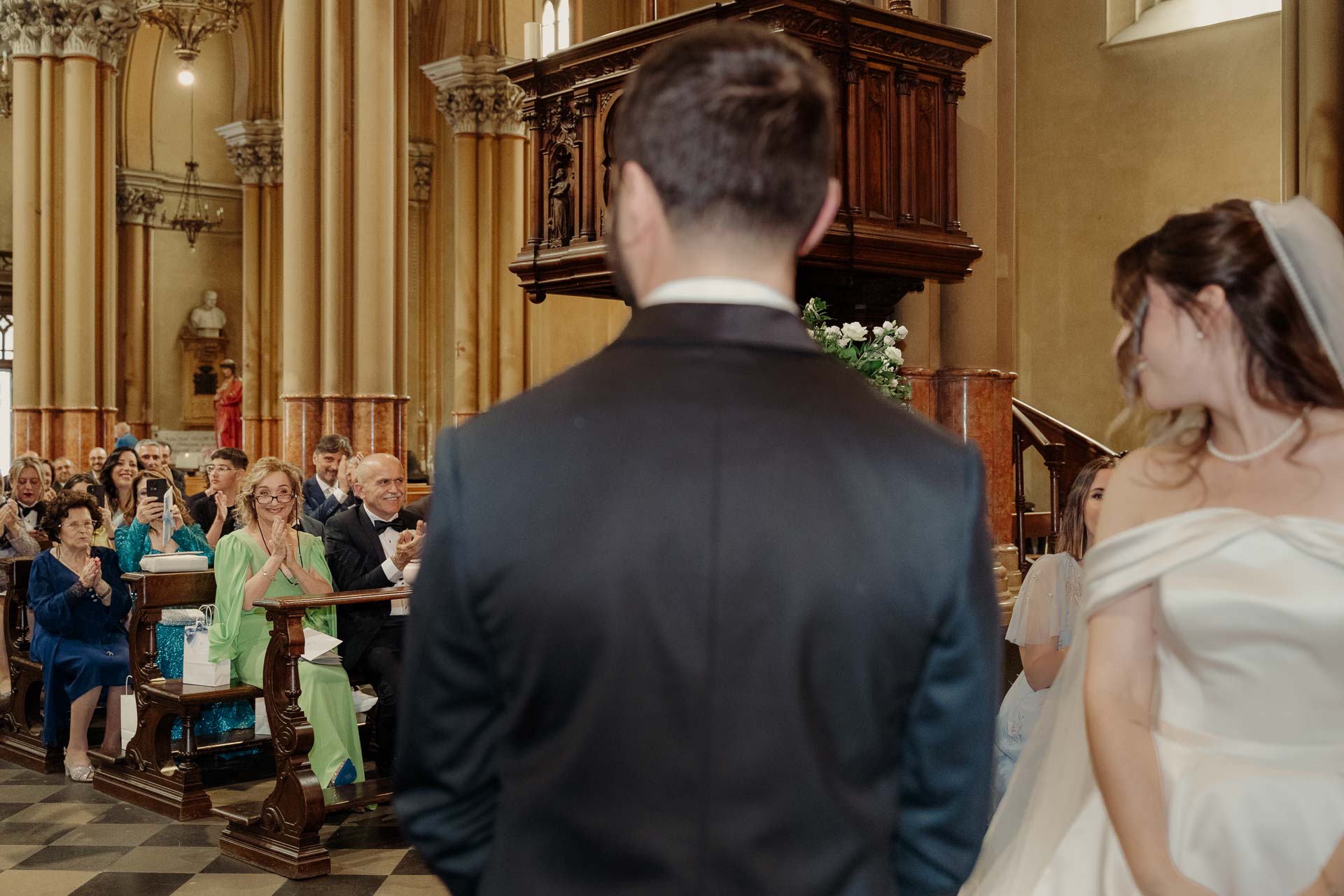 Lo sposo di spalle guarda la sposa all'altare