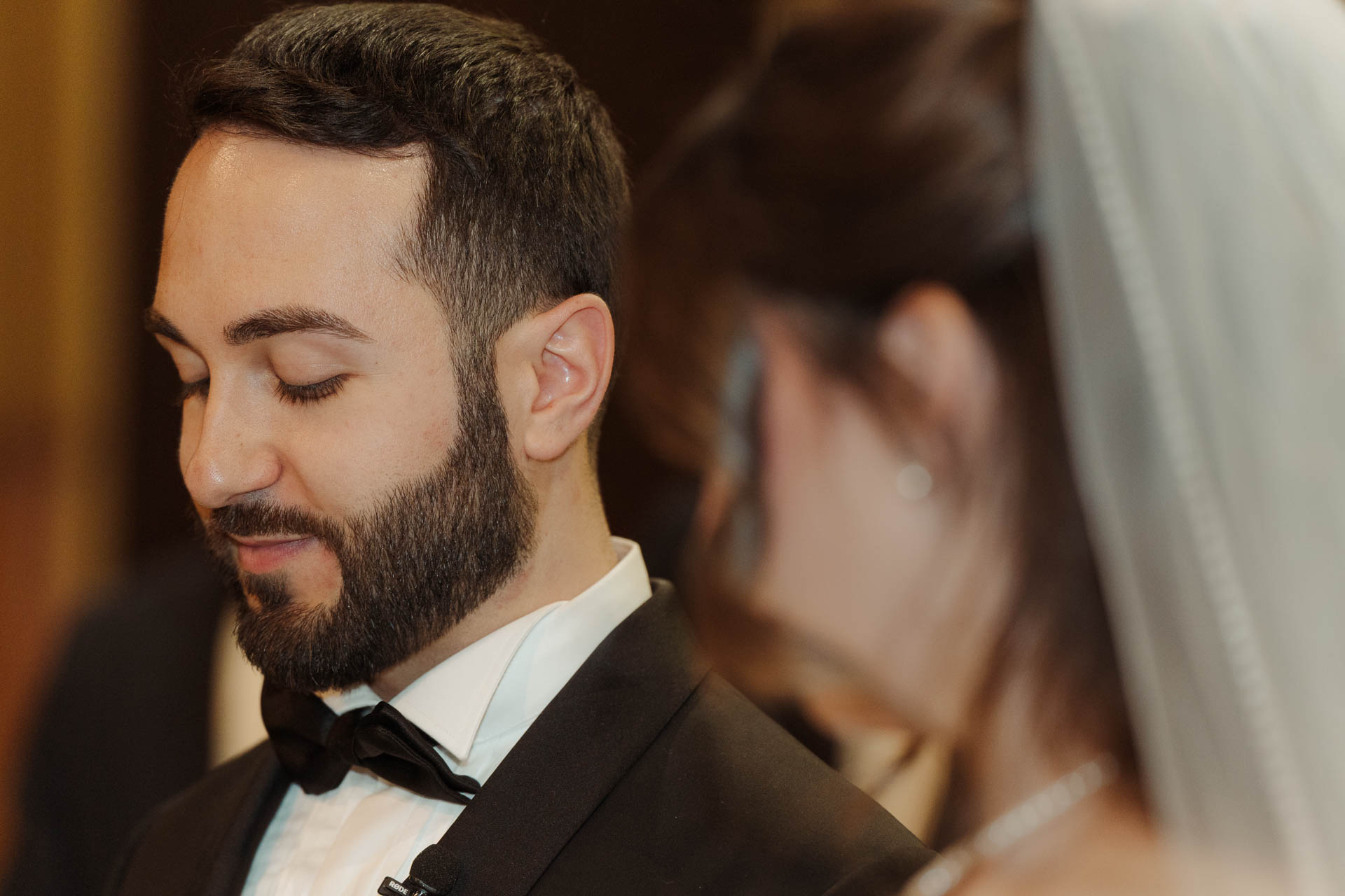 Lo sposo sorride a occhi bassi accanto alla sposa