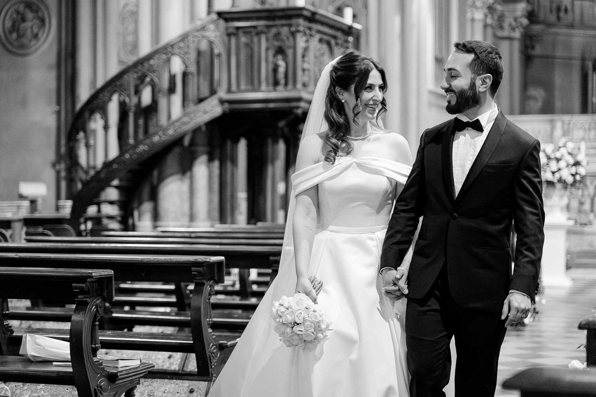 In bianco e nero, gli sposi mano nella mano lungo la navata