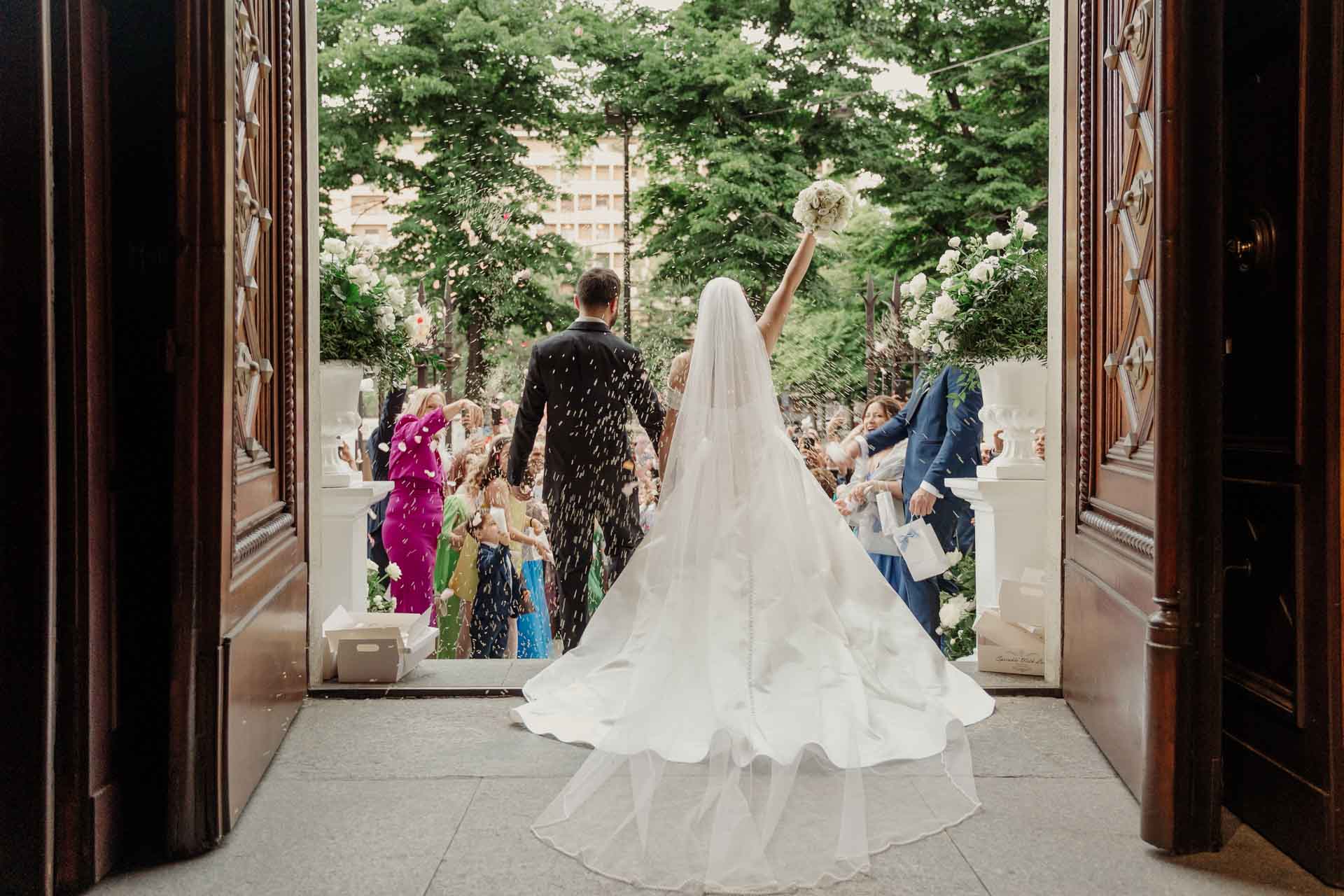 La sposa di spalle sul portone della chiesa, verso gli invitati