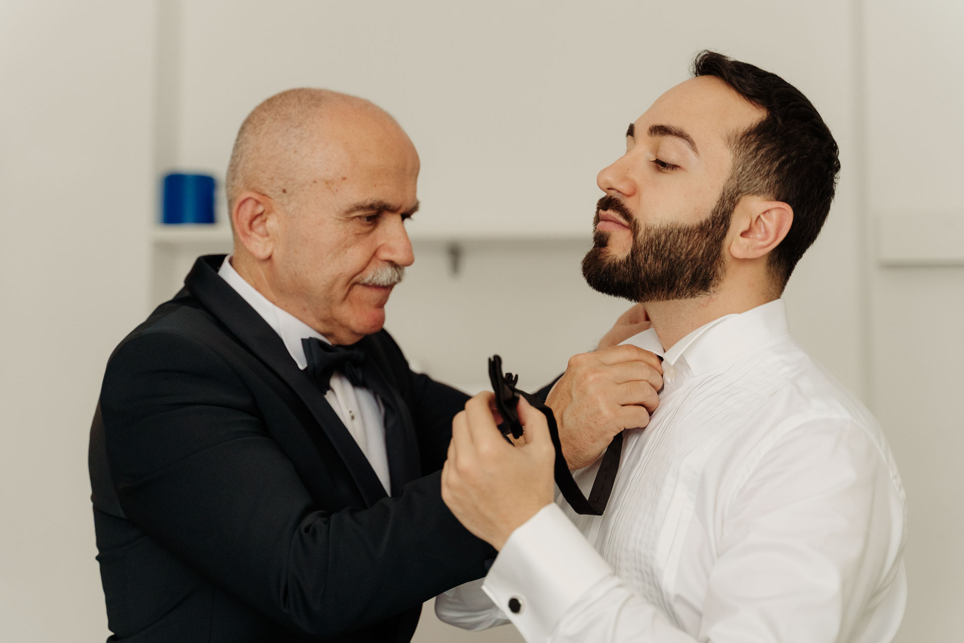 Un signore annoda il papillon allo sposo