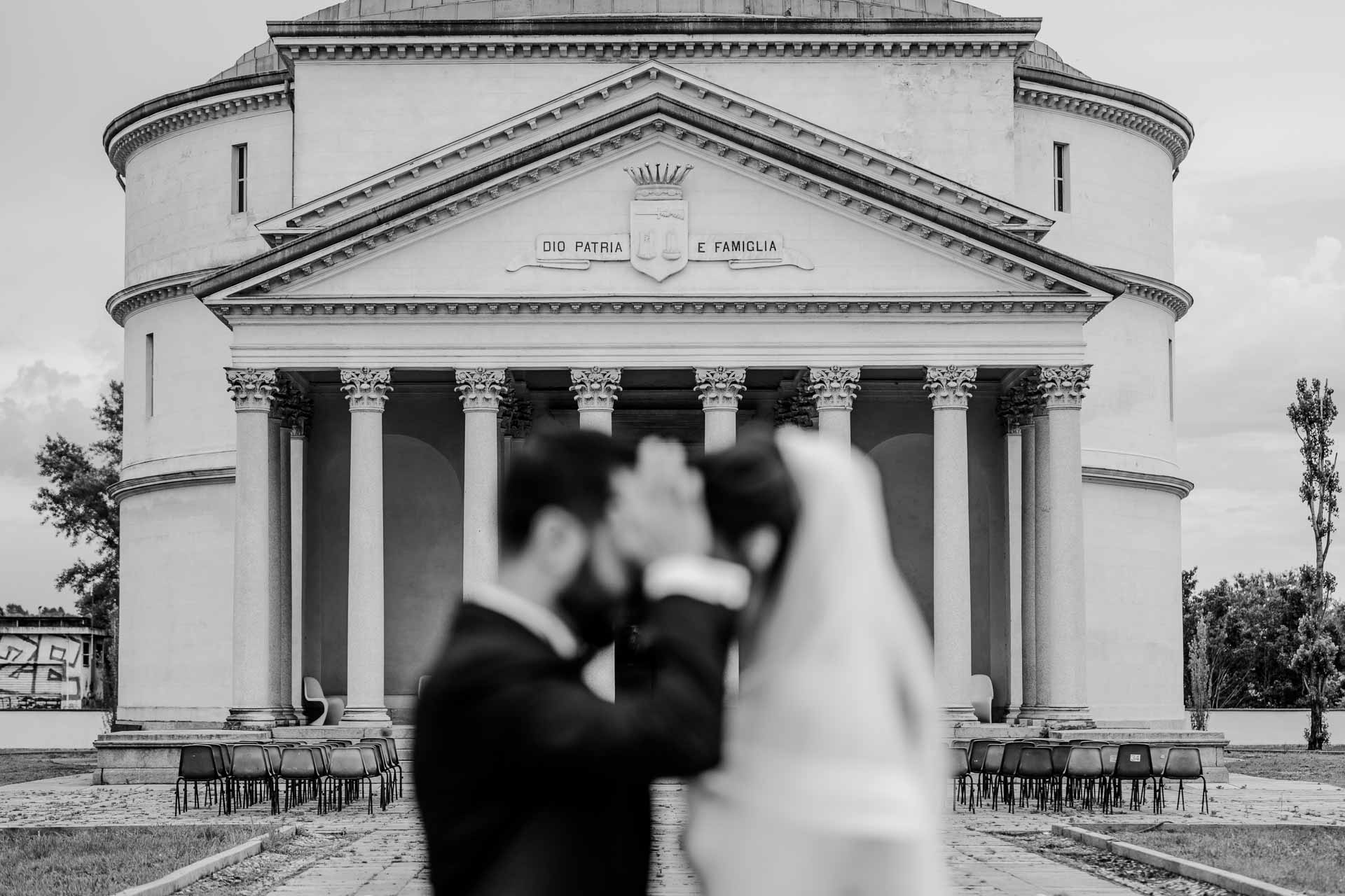 Gli sposi si baciano in primo piano, davanti al mausoleo