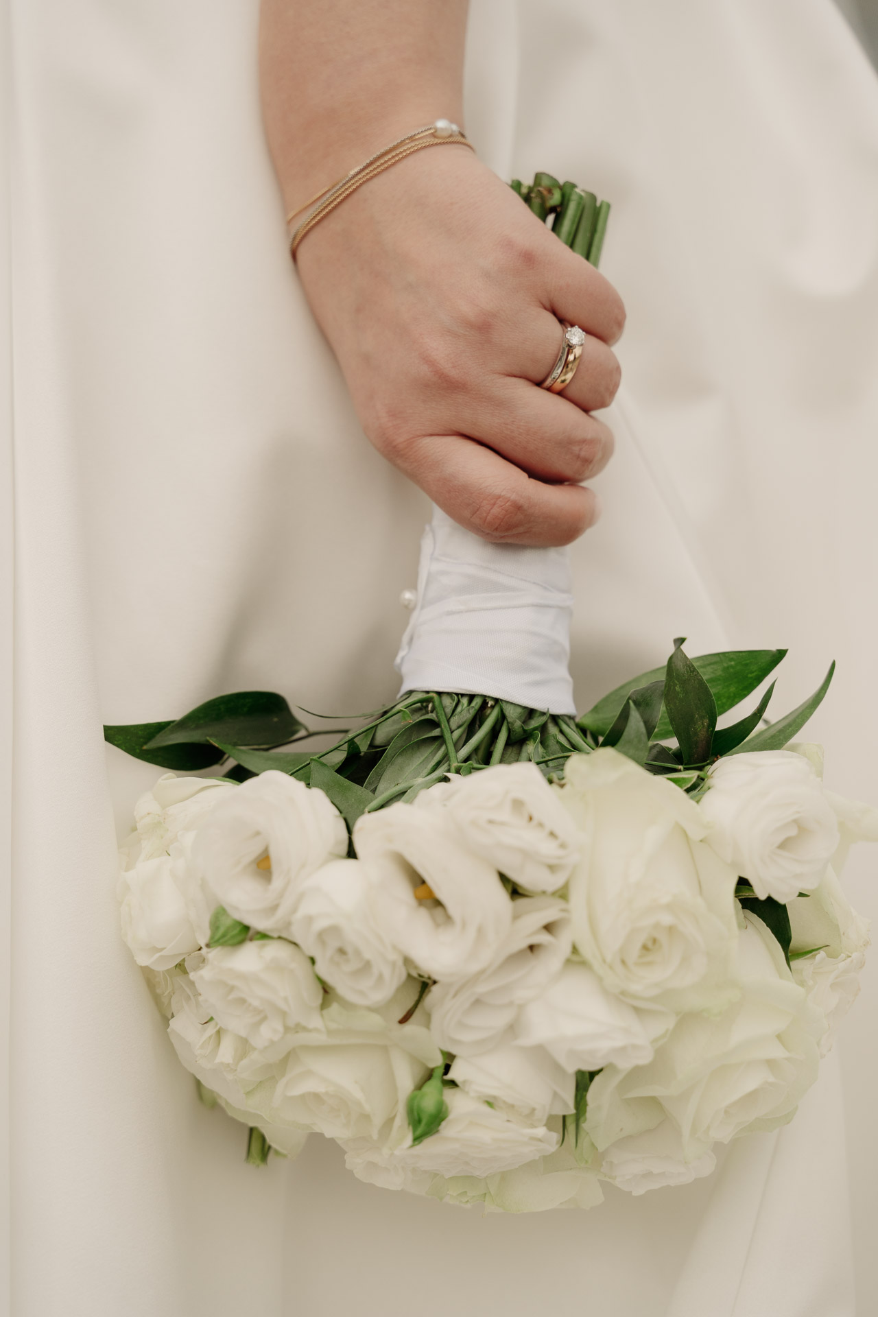 La mano della sposa con l'anello stringe il bouquet