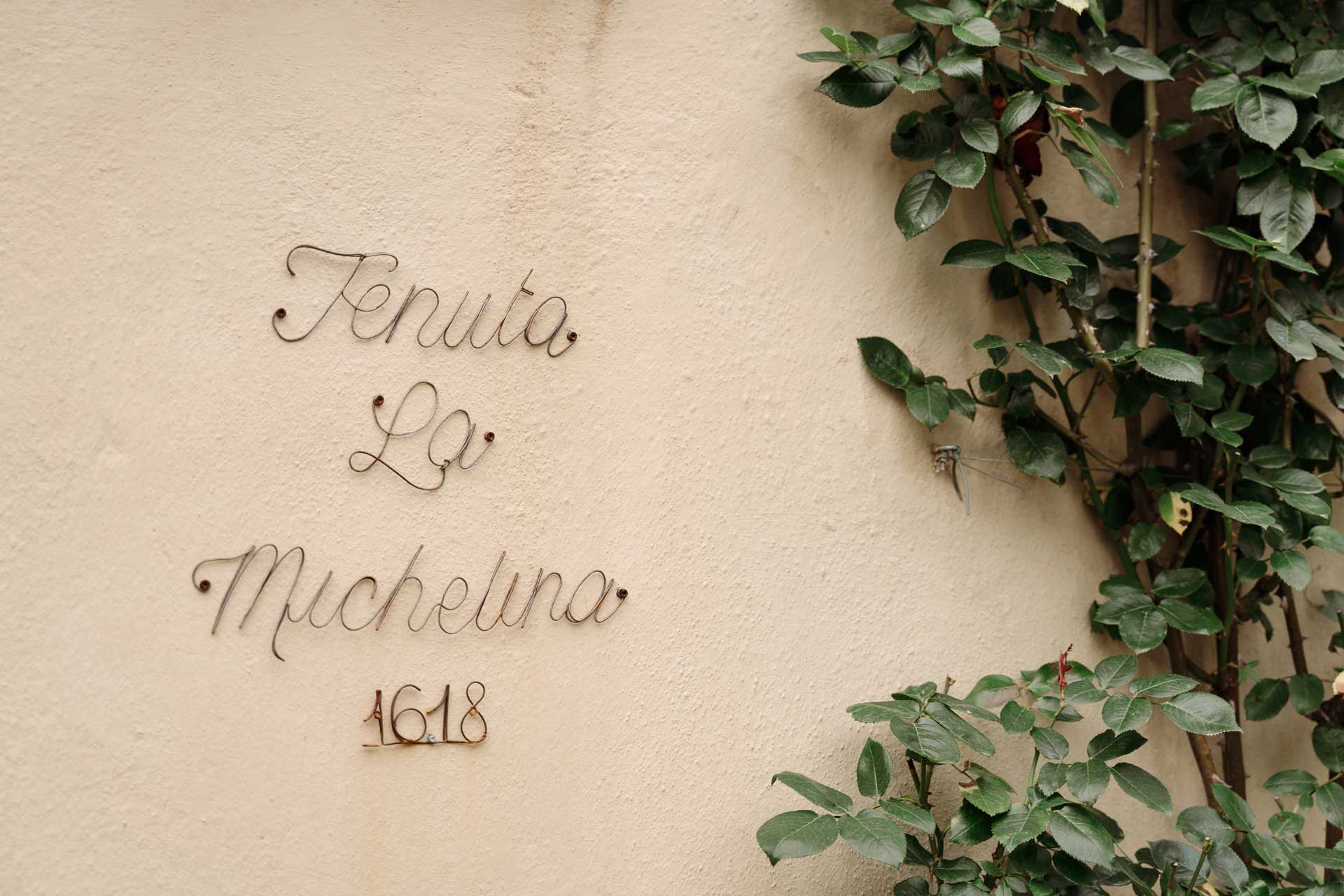 L'insegna della Tenuta La Michelina sul muro, tra le foglie