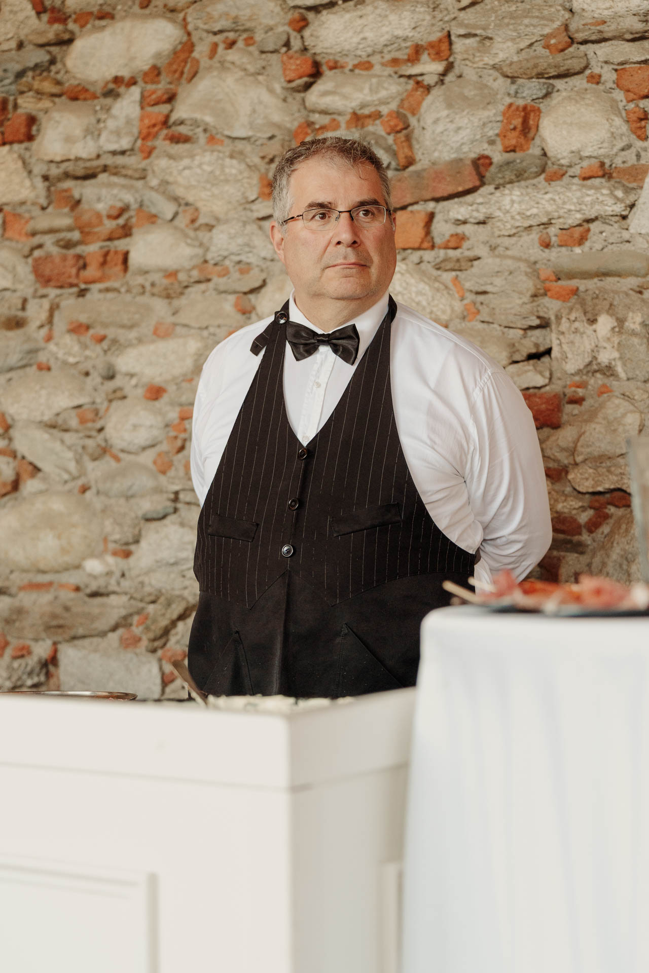 Un cameriere in gilet accanto al buffet