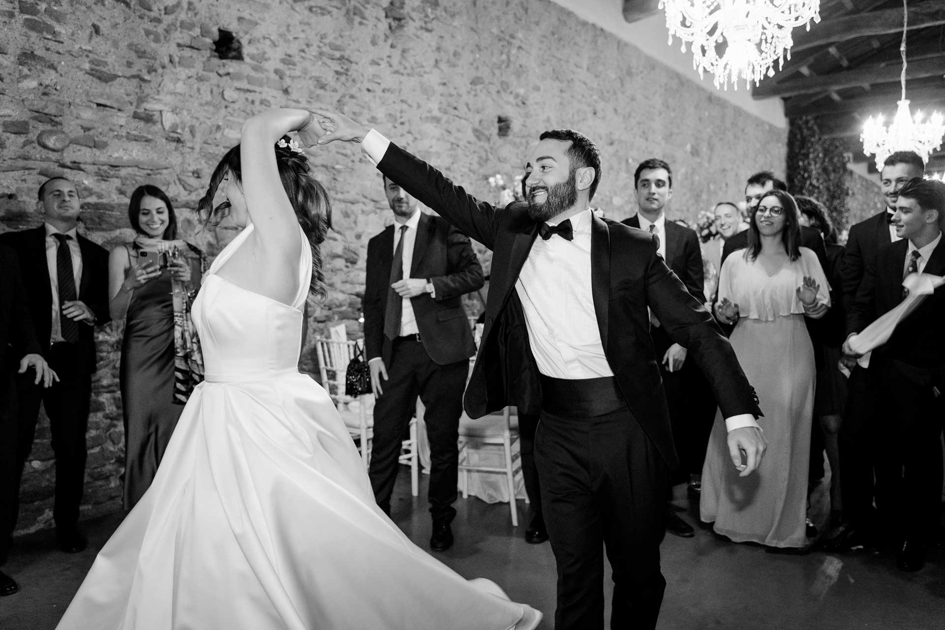 Gli sposi ballano tra gli invitati, sotto il muro di pietra