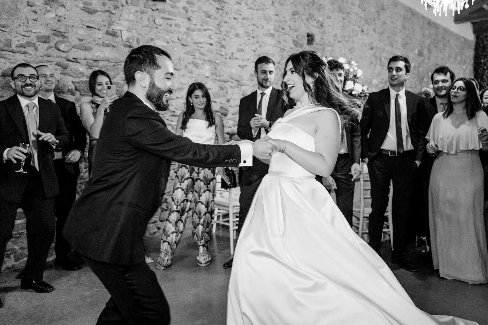 Gli sposi ballano sotto il muro di pietra, tra gli invitati