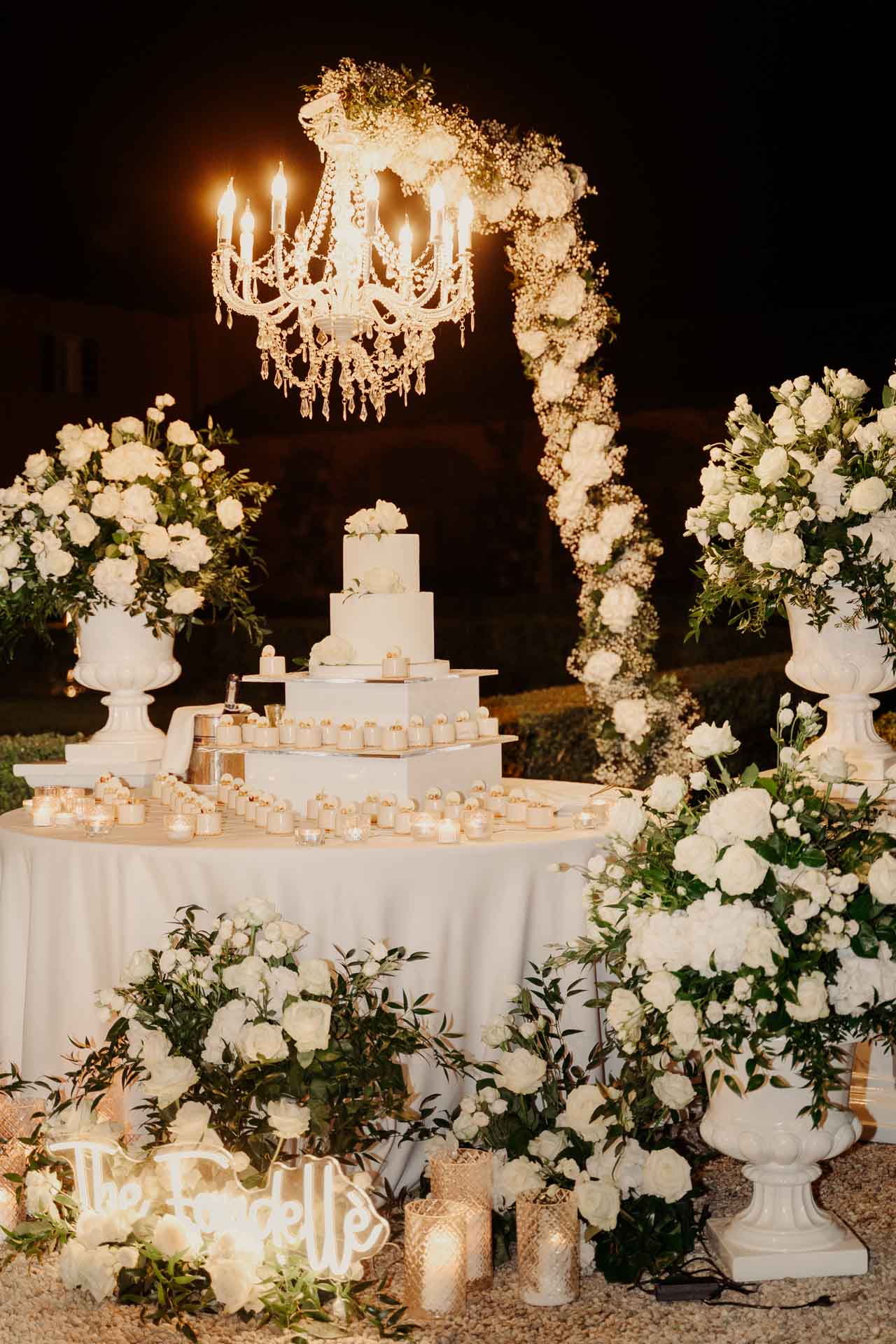 La torta nuziale sotto il lampadario, tra rose bianche e candele