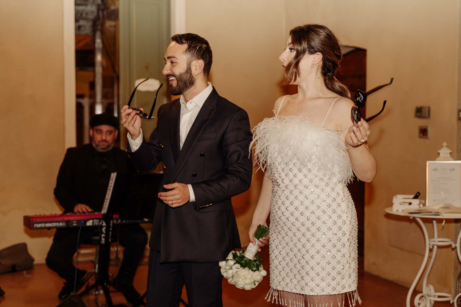 Gli sposi negli abiti della sera ridono accanto al pianista