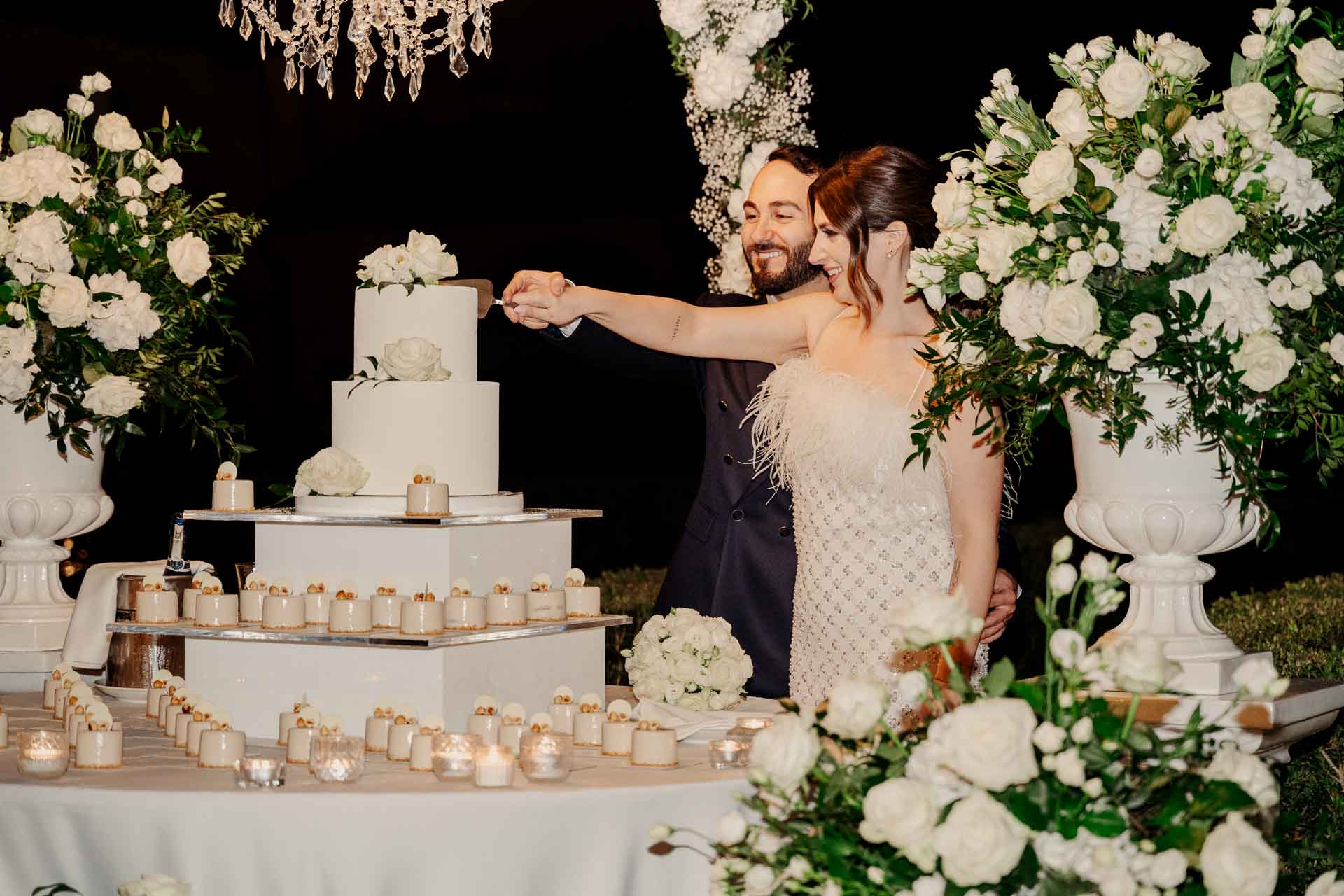Gli sposi tagliano la torta nuziale tra i fiori bianchi