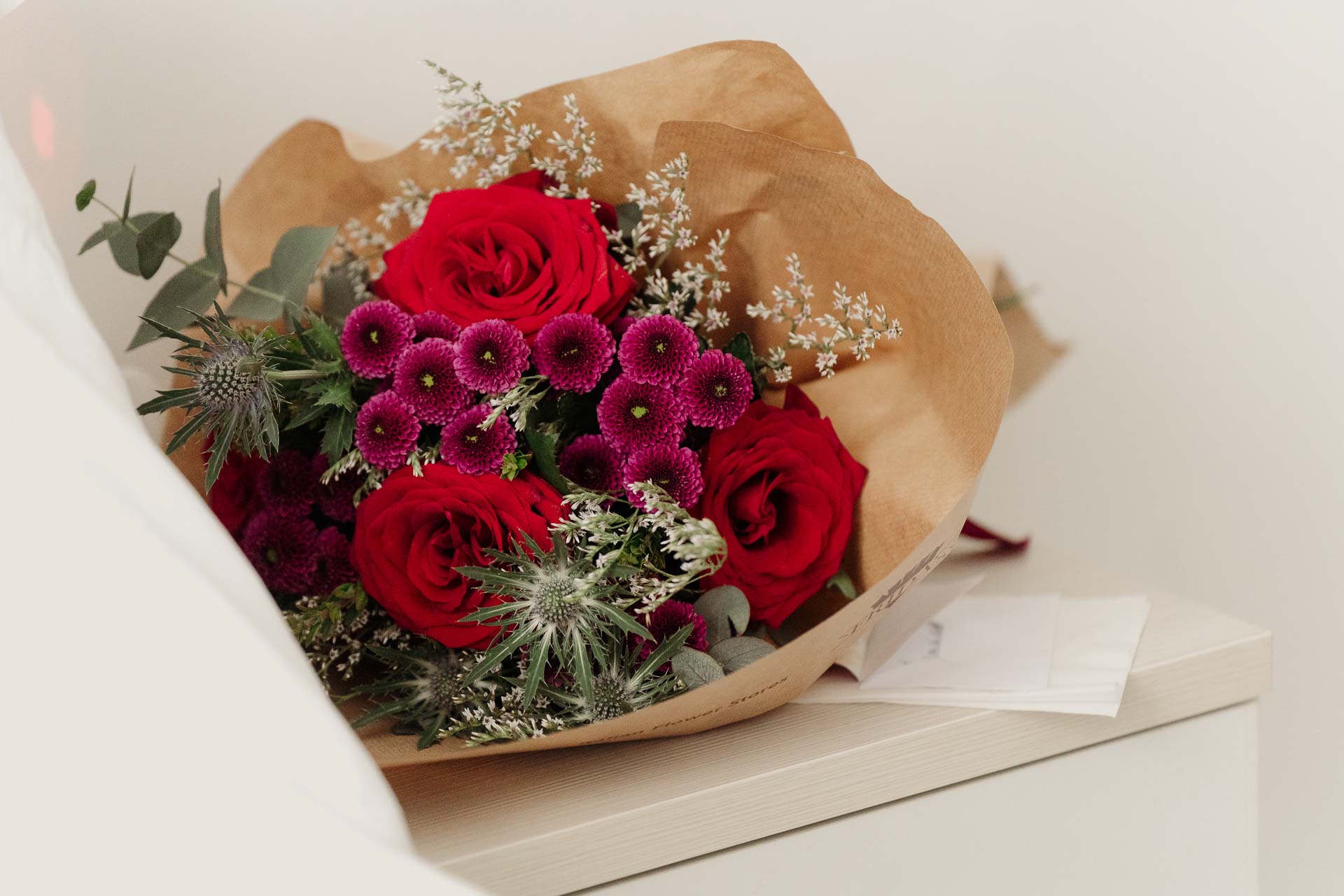 Il bouquet di rose rosse e fiori viola nella carta