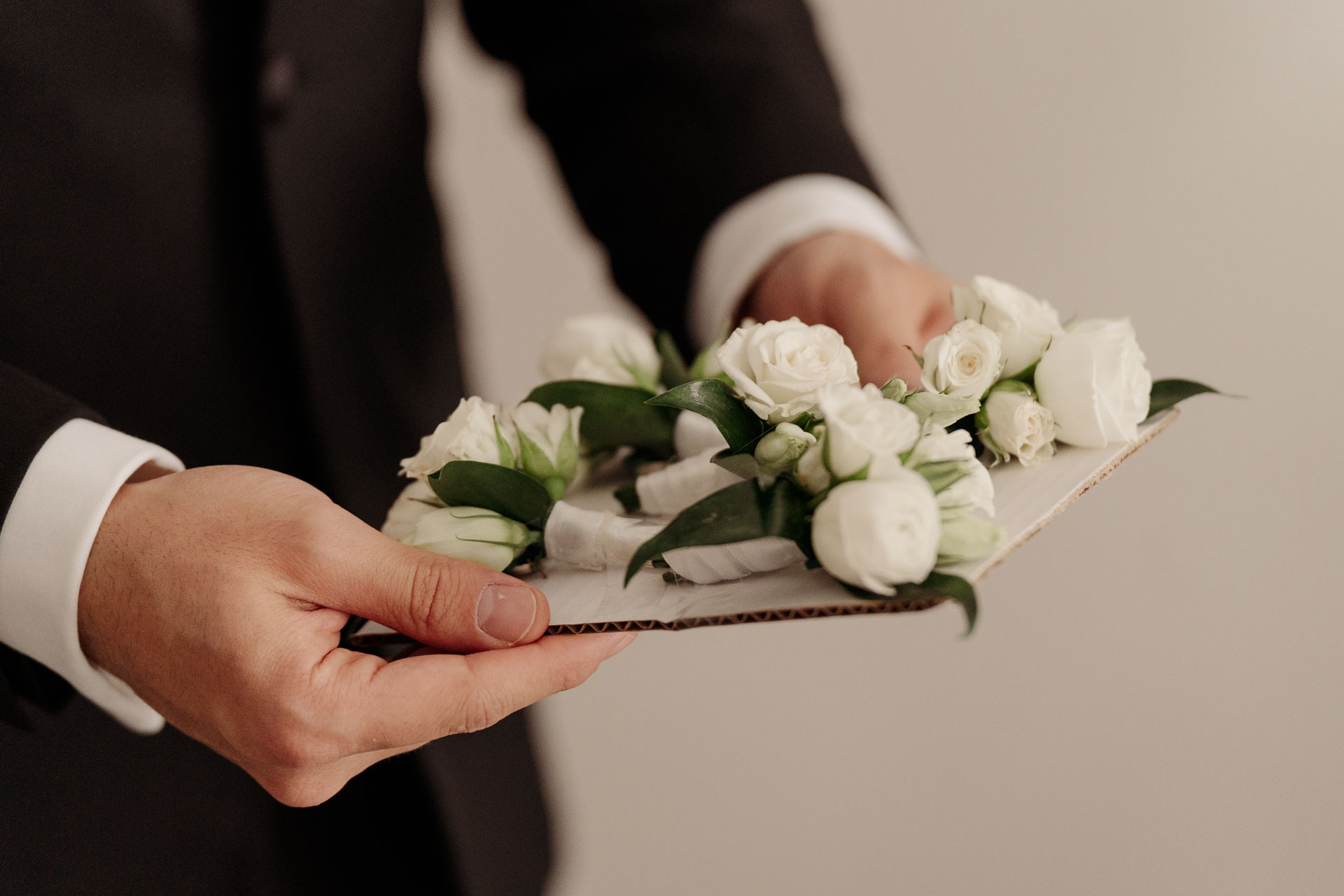I fiori all'occhiello di rose bianche nella mano dello sposo
