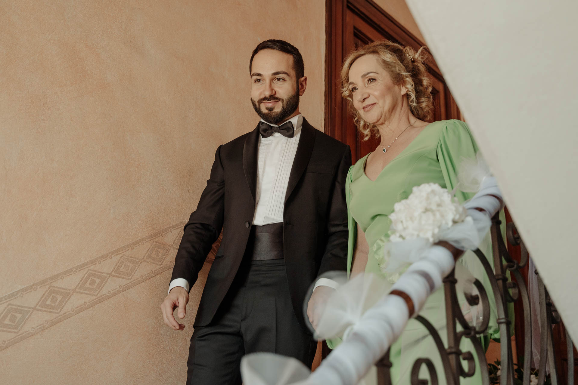 Lo sposo scende le scale accanto alla signora in verde