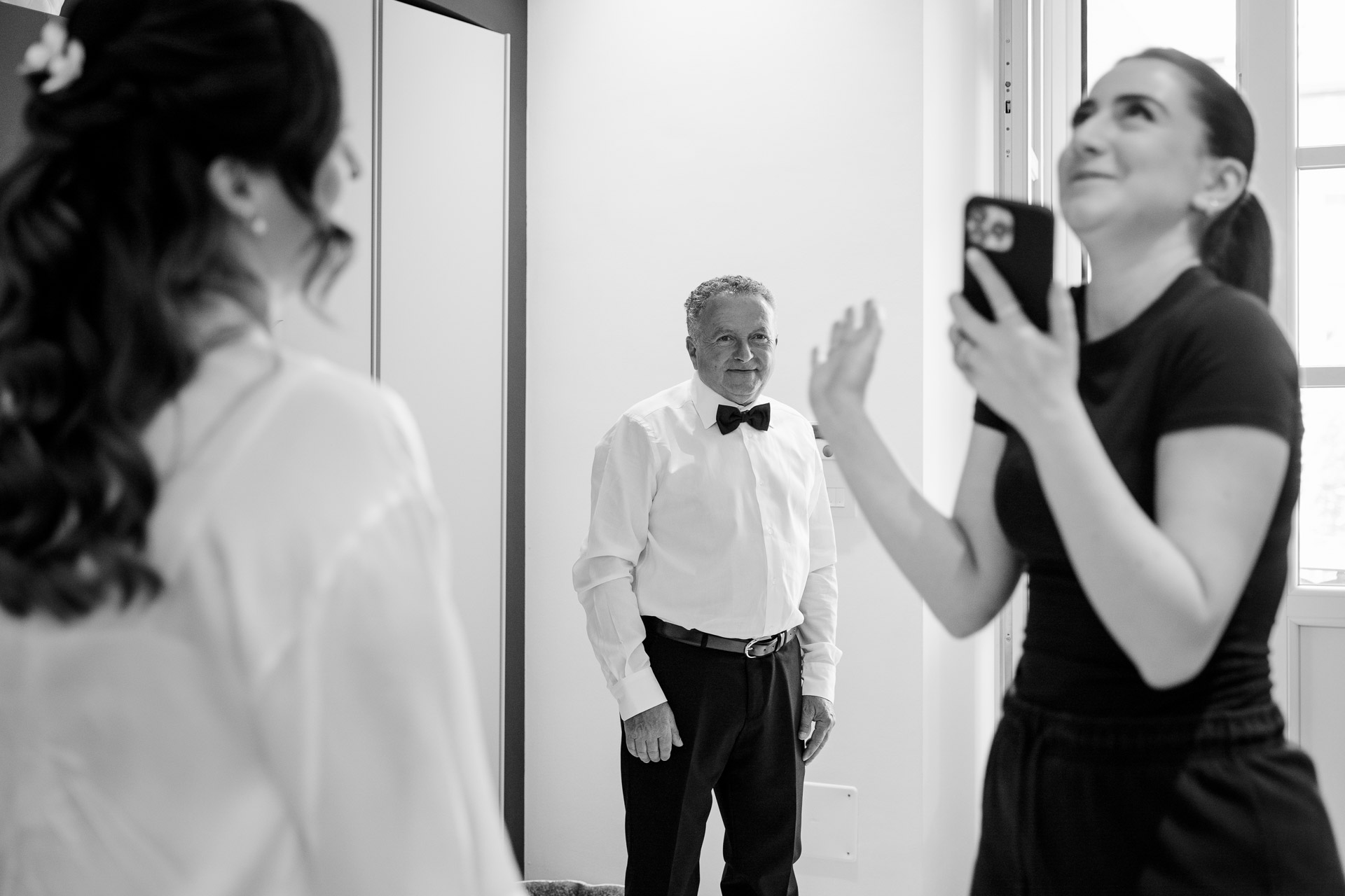 In bianco e nero, un signore guarda la sposa dalla porta