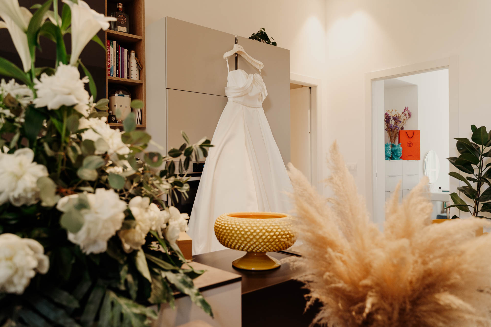 L'abito da sposa appeso tra i fiori bianchi del soggiorno