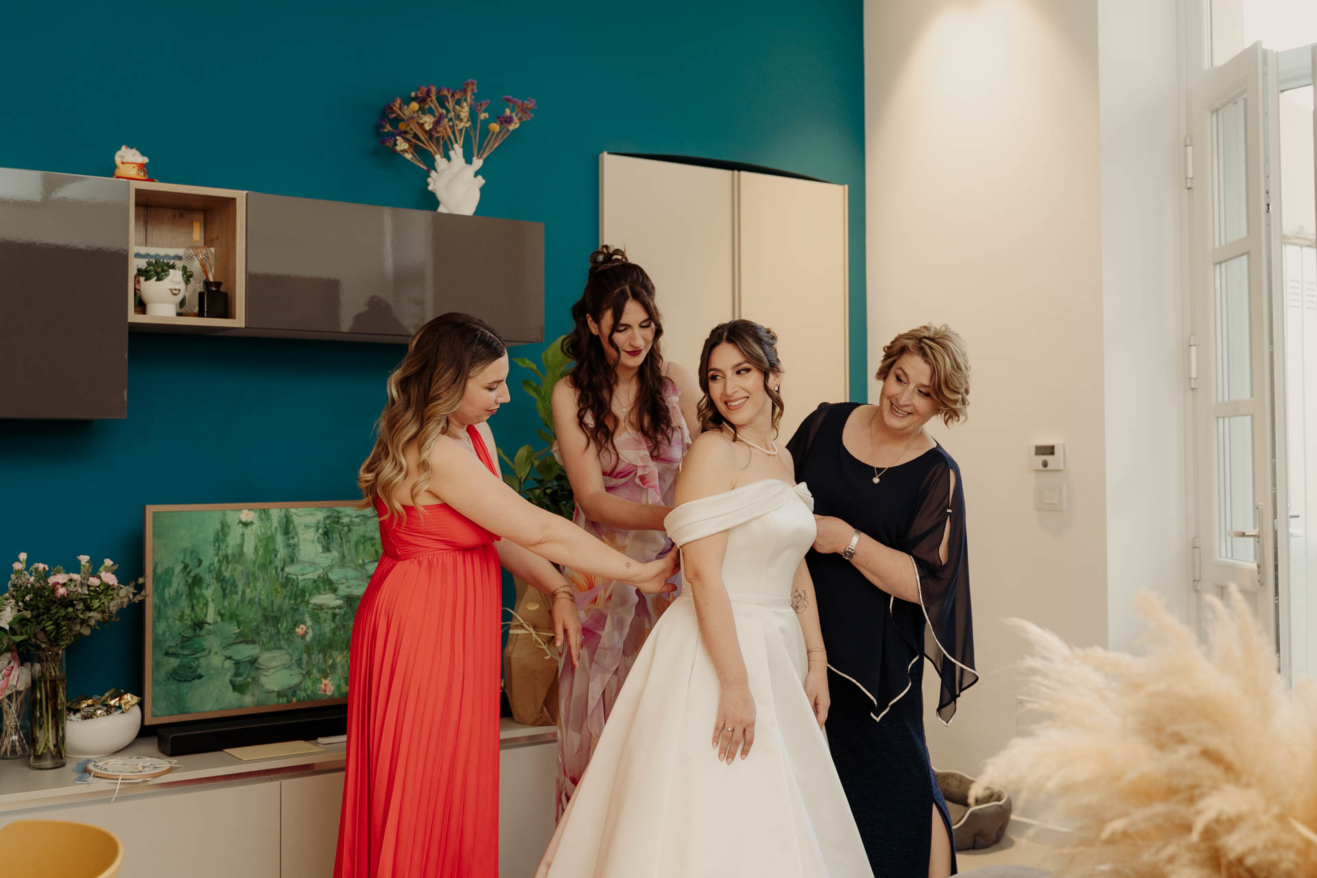 Tre donne aiutano la sposa a chiudere l'abito