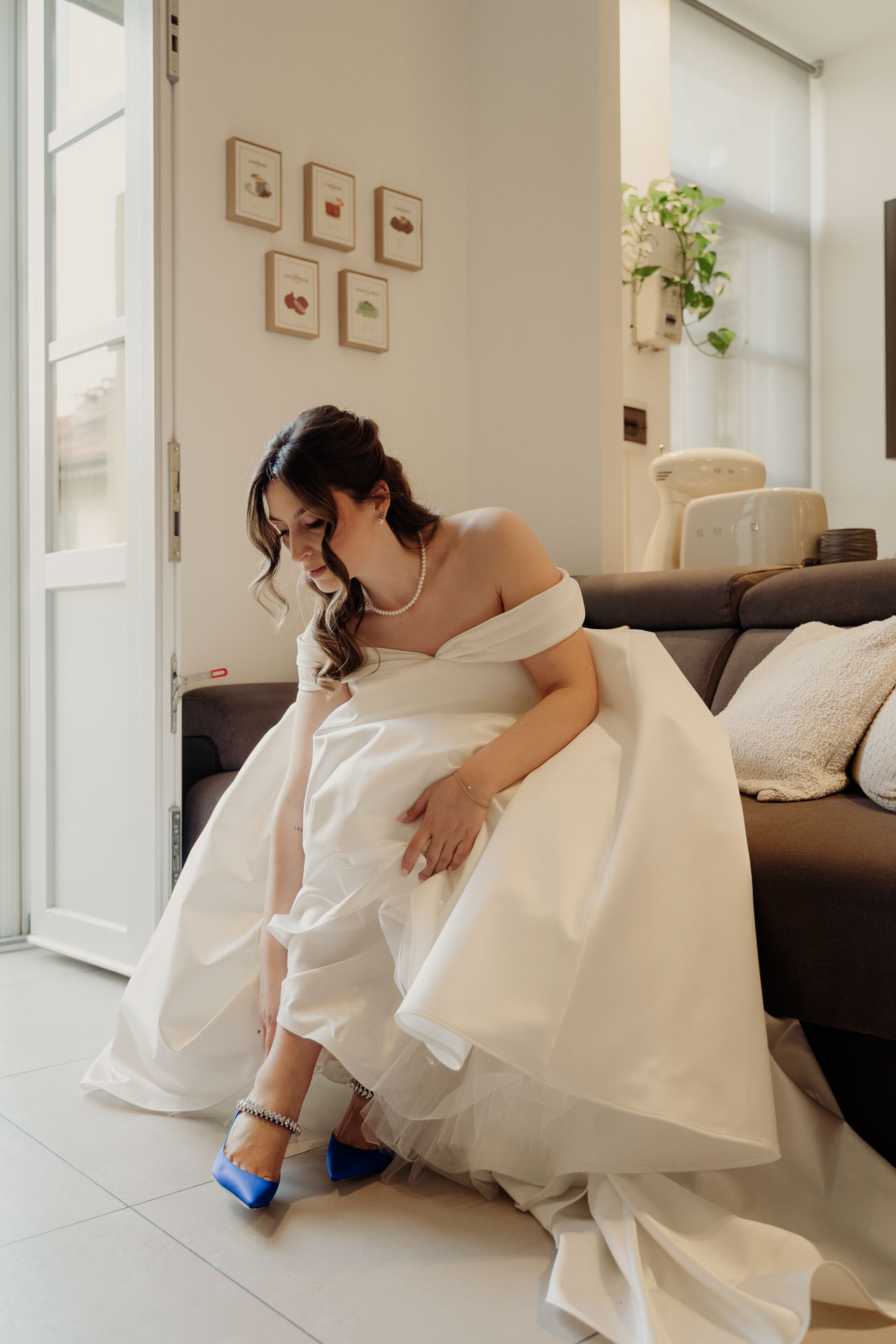 La sposa si infila le scarpe blu, seduta sul divano