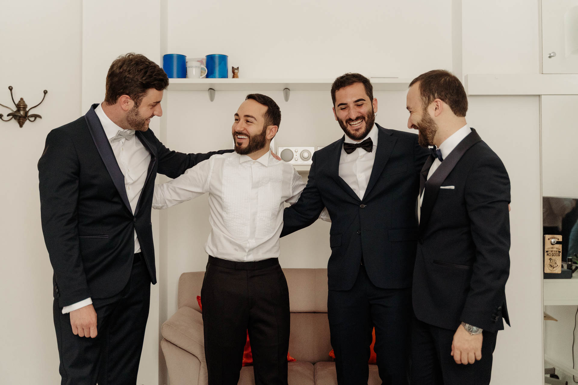Lo sposo abbracciato agli amici in smoking
