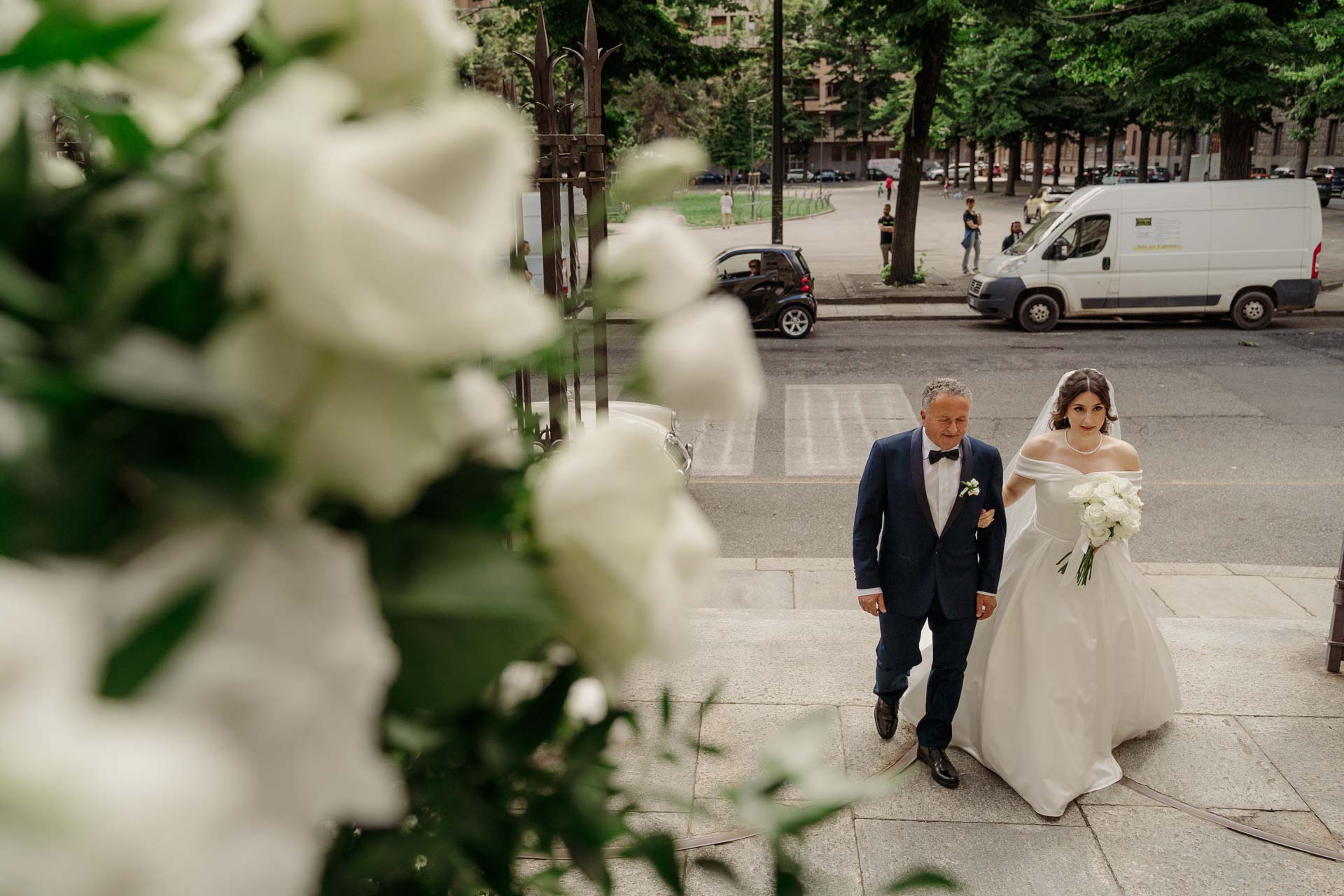 La sposa arriva alla chiesa sottobraccio a un signore, vista tra i fiori