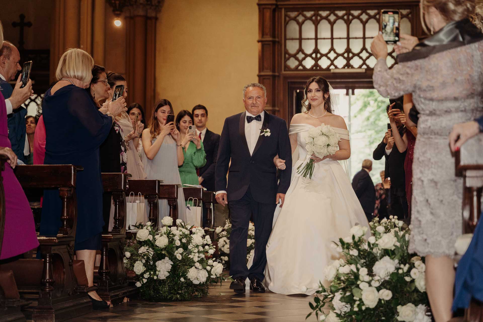La sposa percorre la navata sottobraccio, tra gli invitati