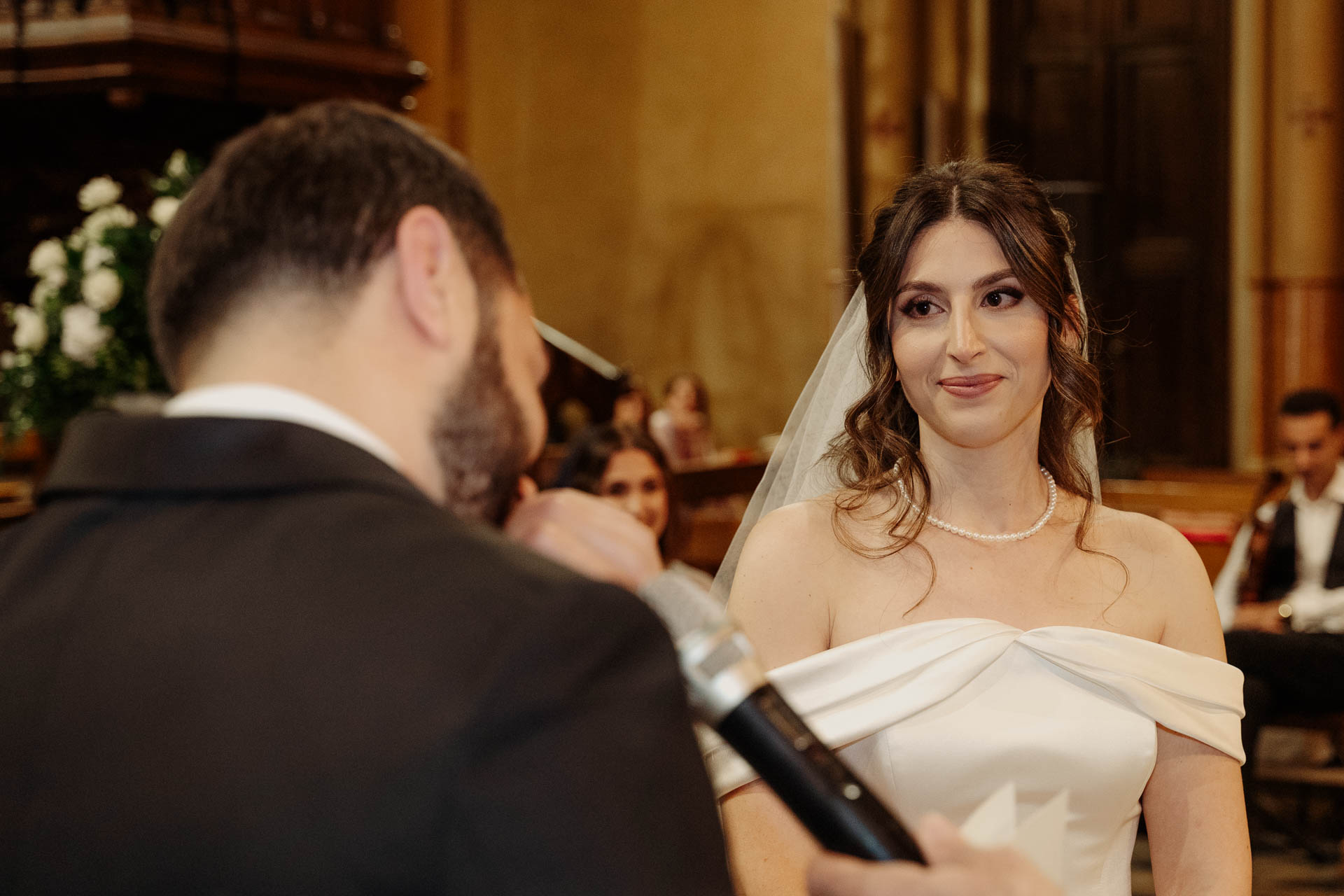 La sposa sorride mentre lo sposo legge al microfono