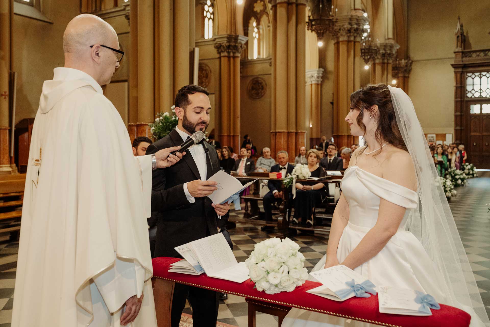 Gli sposi e il celebrante davanti all'altare, con gli invitati