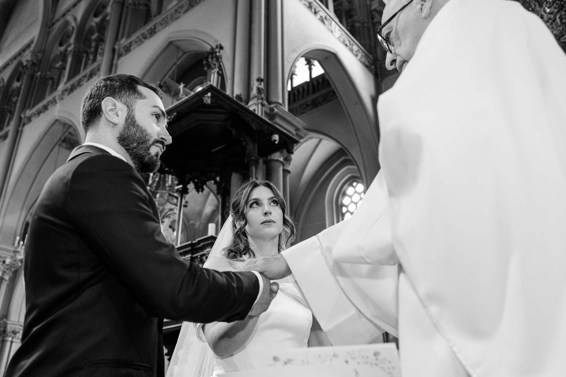 In bianco e nero, il celebrante stringe le mani degli sposi