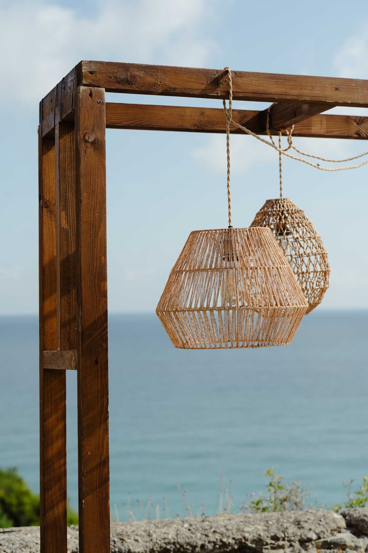 Le lanterne di vimini appese a un portale di legno, davanti al mare