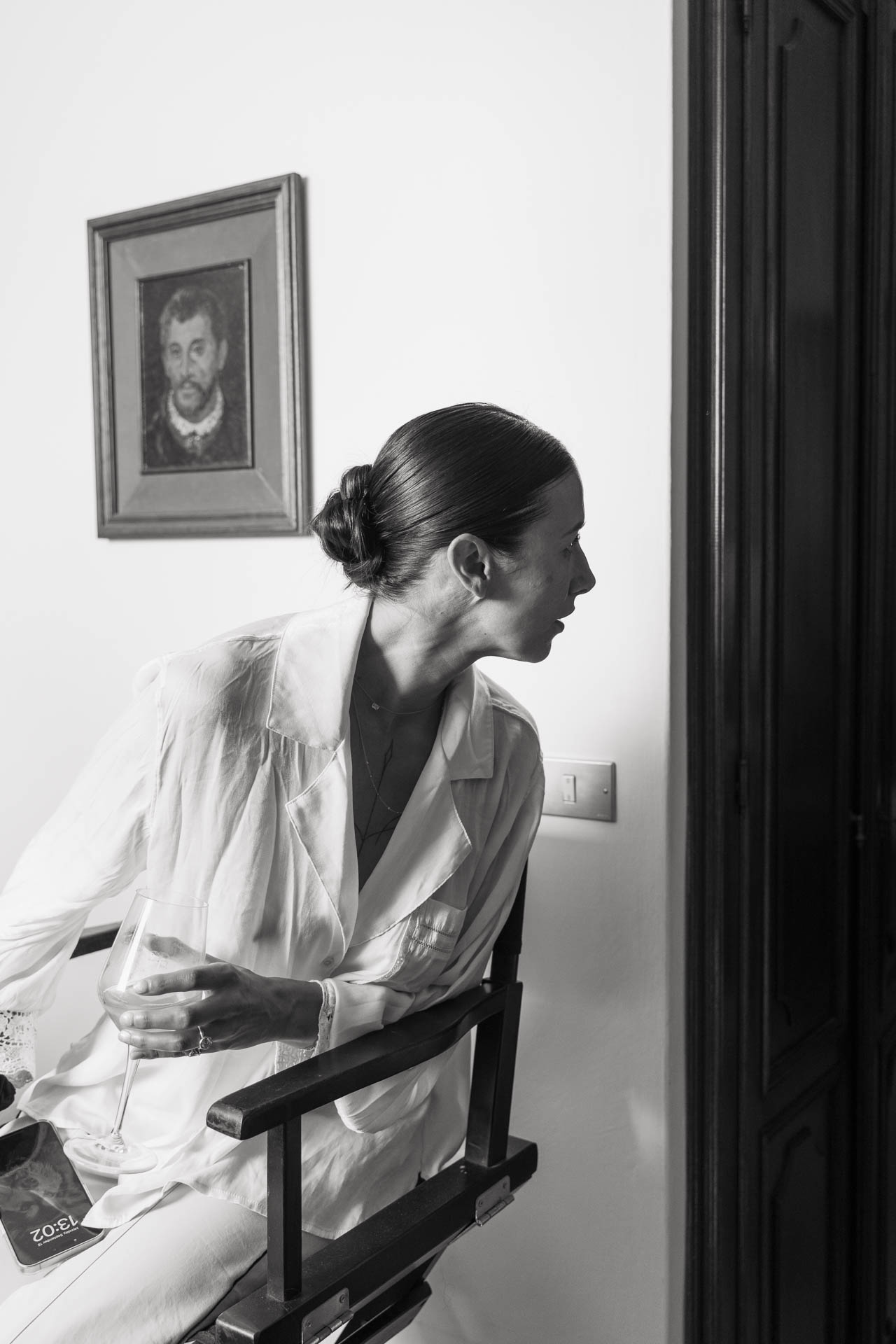 In bianco e nero, la sposa seduta sulla sedia del trucco guarda verso la porta