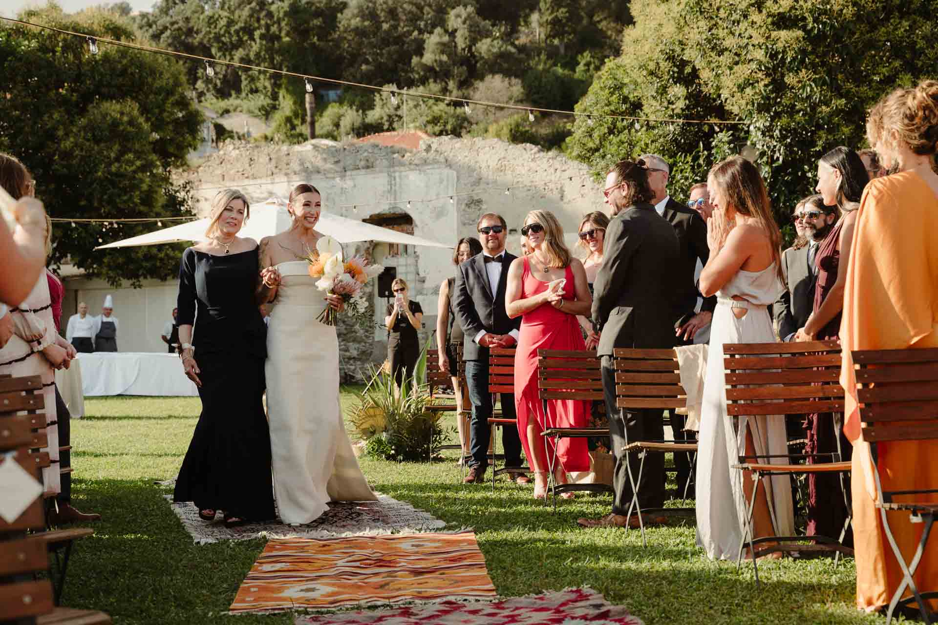 La sposa e la sua accompagnatrice tra gli invitati in piedi